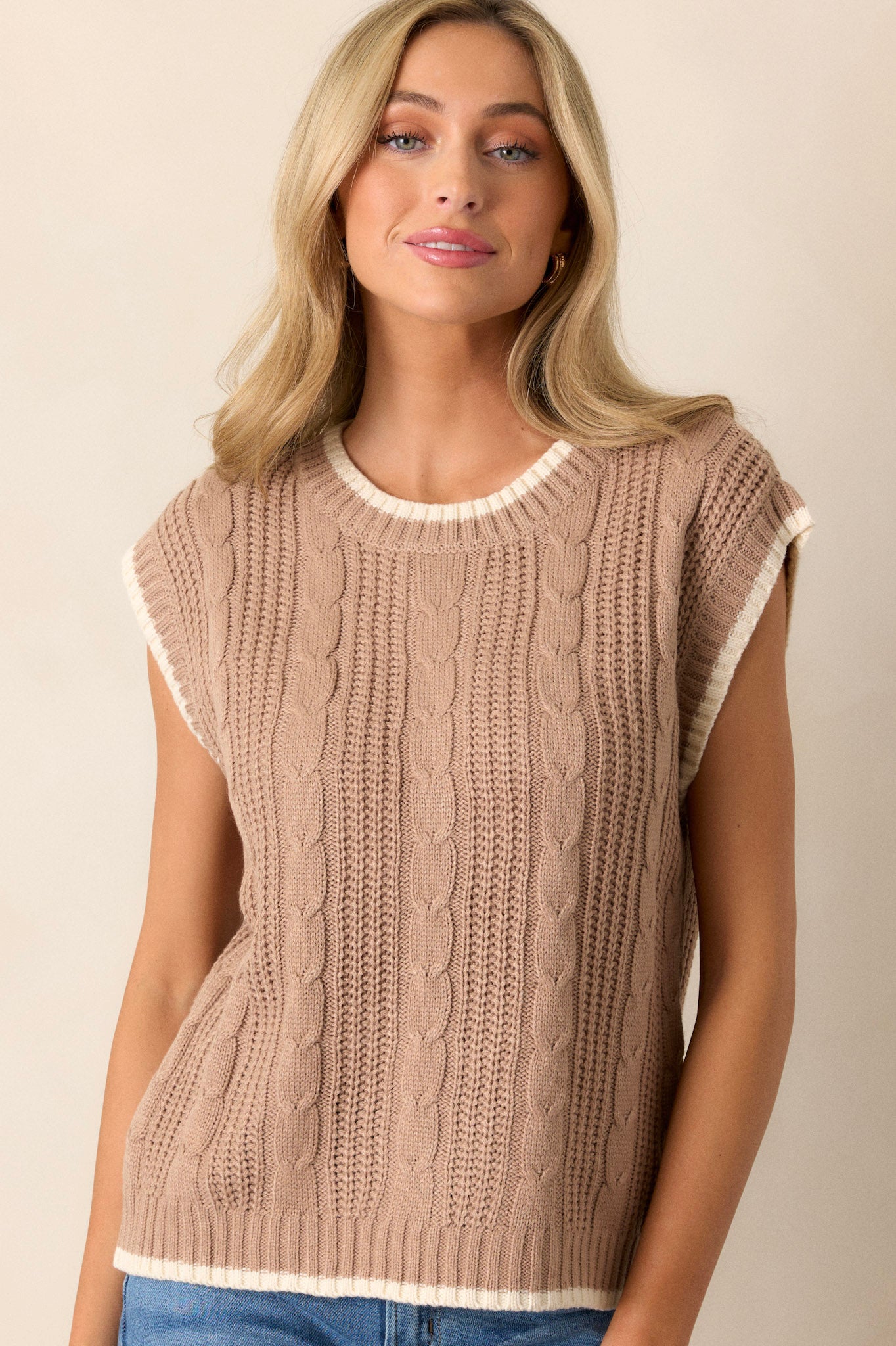 Front view of a knit sweater top featuring a high rounded neckline, a soft knit texture, cap sleeves, and an ivory trim.