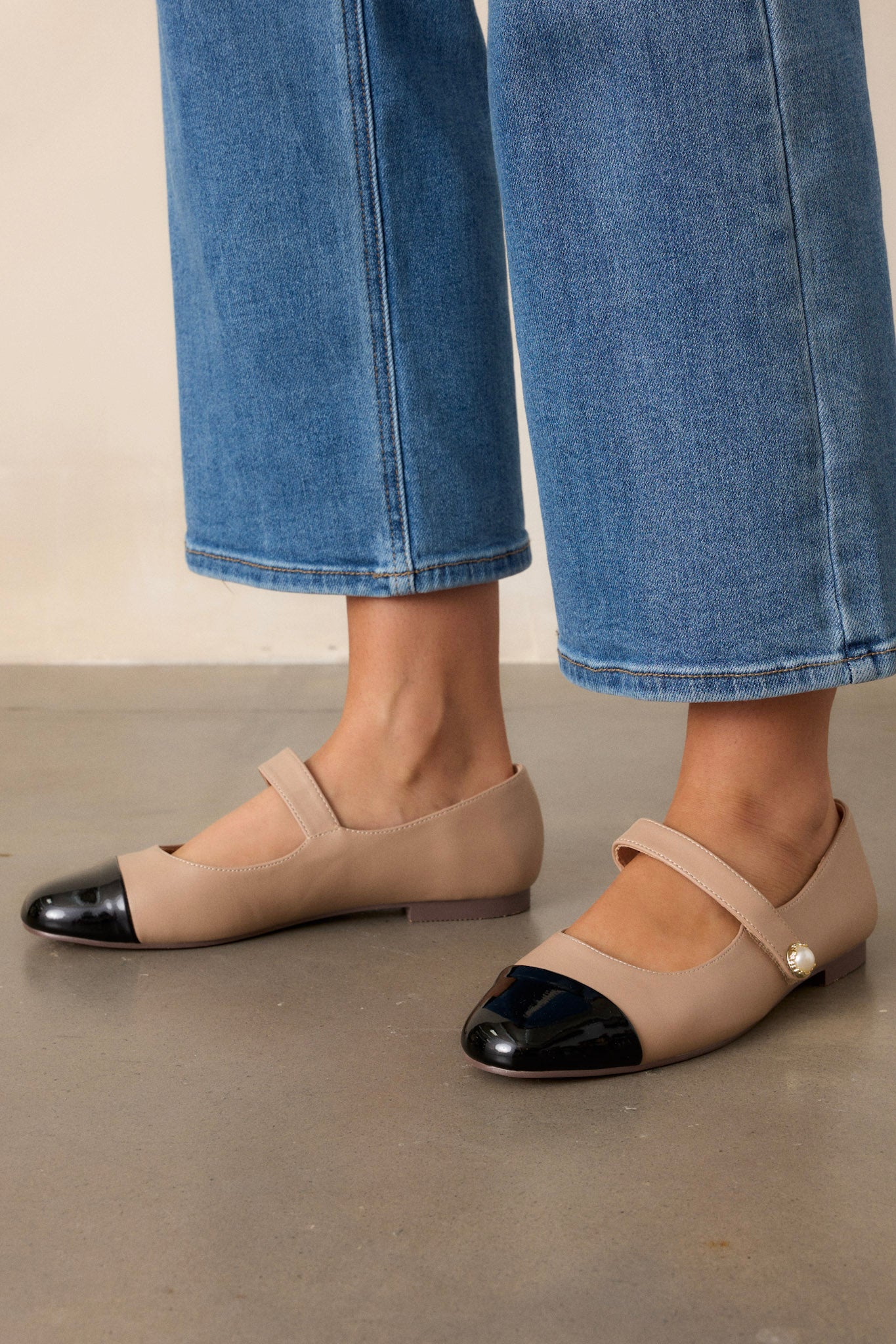 Side view of the tan flats, highlighting the glossy black round toe and the smooth matte finish of the tan material.