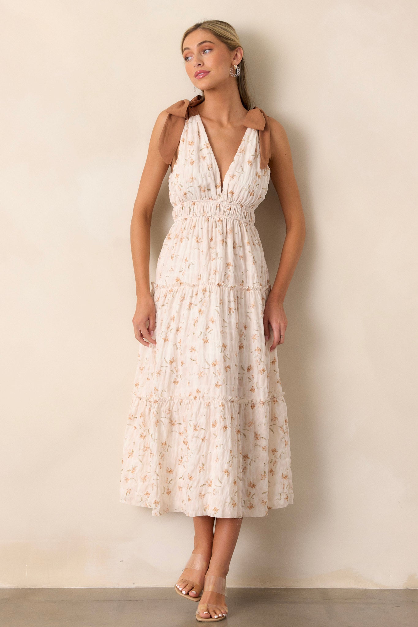 This dress features a plunge neck detail, a smocked waistband and two tie straps for the shoulders.