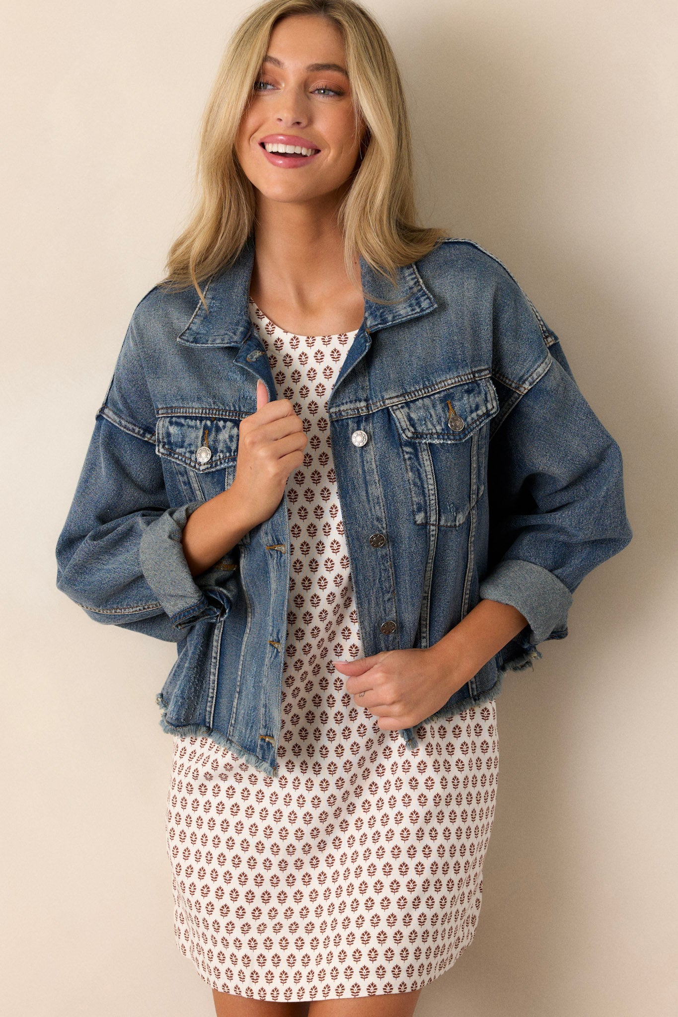 This denim jacket features buttons up the front, a folded collar, functional chest pockets, distressed details, and prominent dolman sleeves.