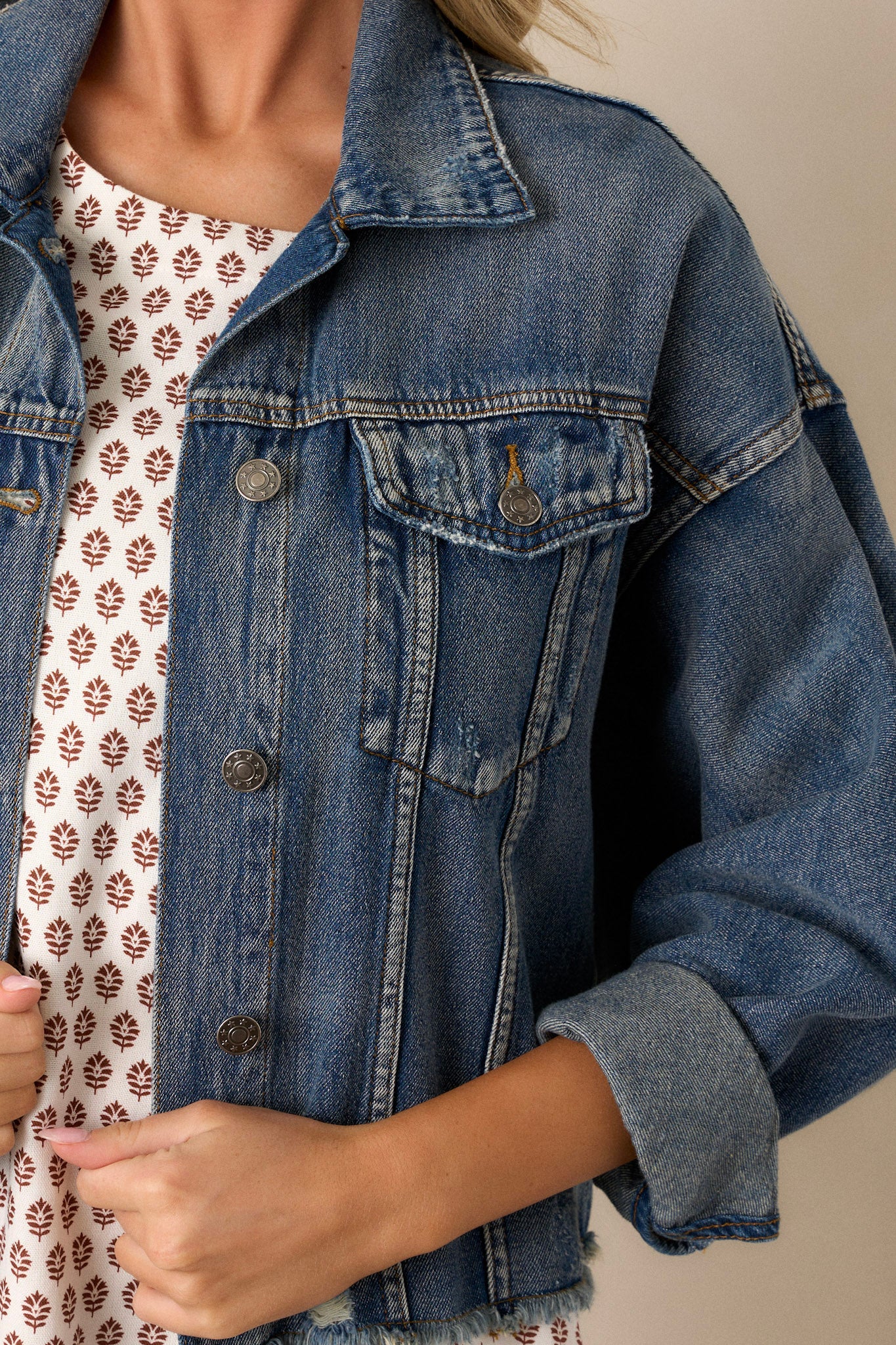 Close-up of the denim jacket focusing on the button-up front, folded collar, distressed details, and the texture of the prominent dolman sleeves.