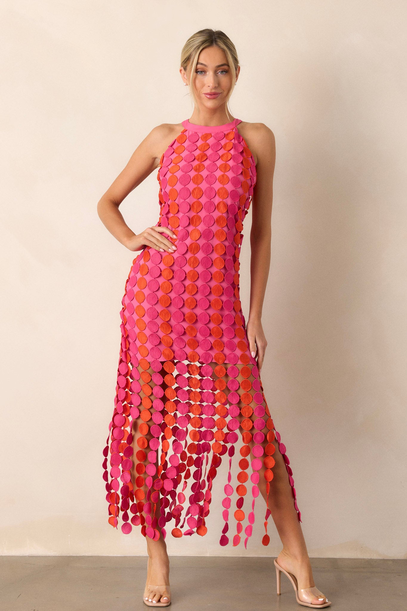 Full-length view of a model wearing the dress, emphasizing the pink and orange fun fringe, the tie halter neckline, and the functional zipper