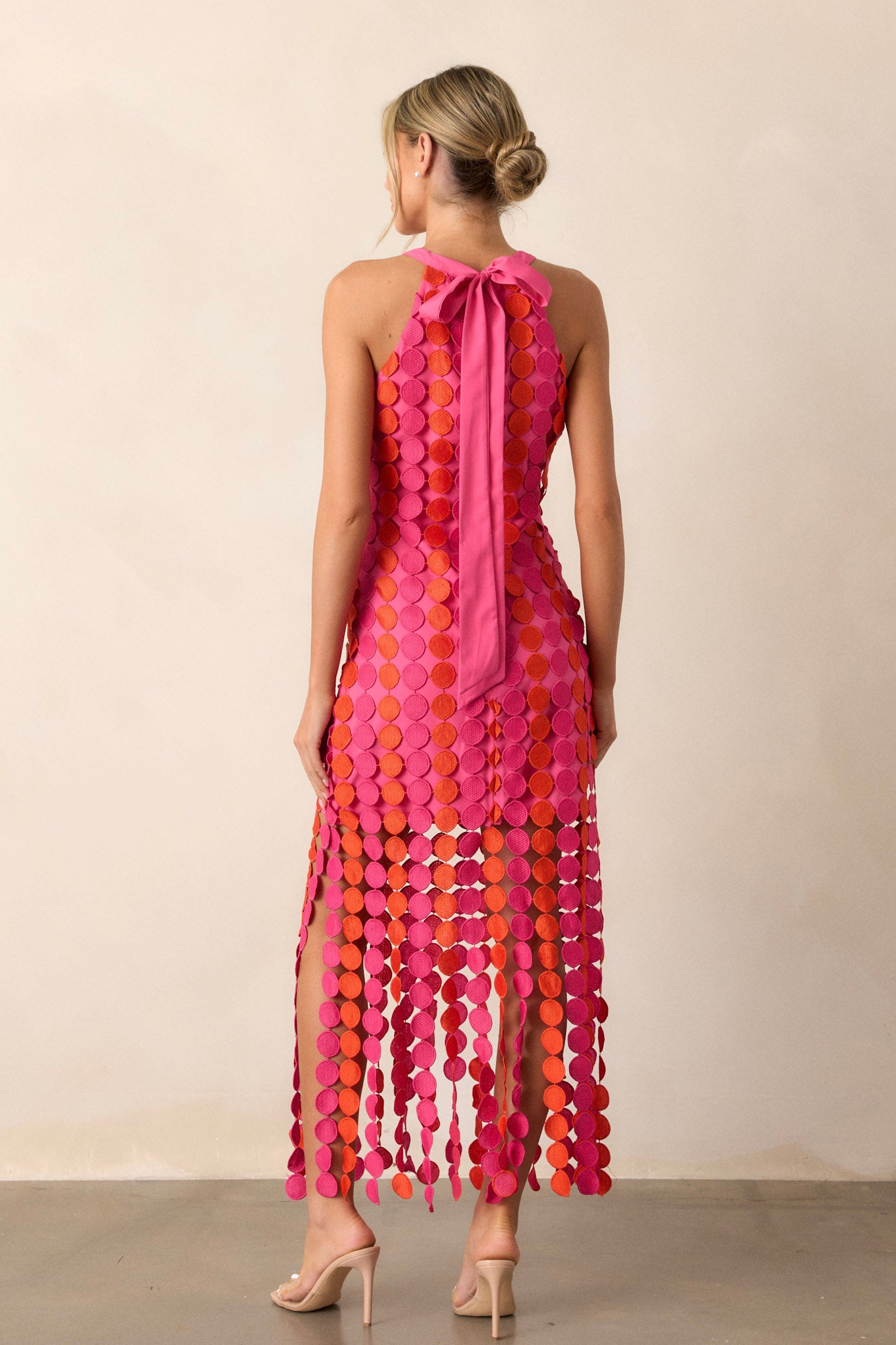 Back view of the dress highlighting the tie halter detail and the functional zipper, with the pink and orange fringe adding texture and movement.