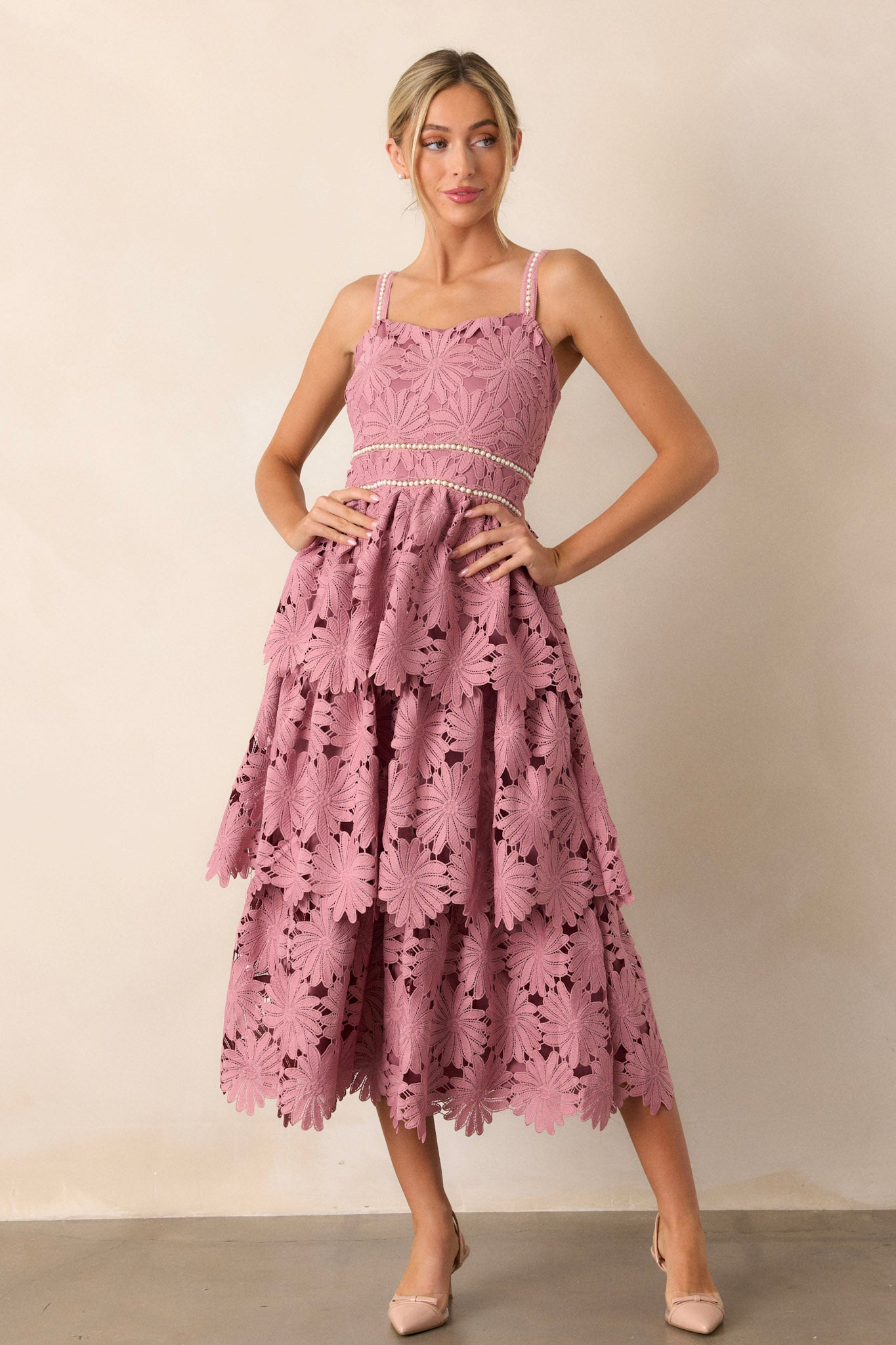 This dusty pink dress features a square neckline, a faux pearl decorated waistline, a lace tiered design, a discrete back zipper and faux pearl decorated spaghetti straps.