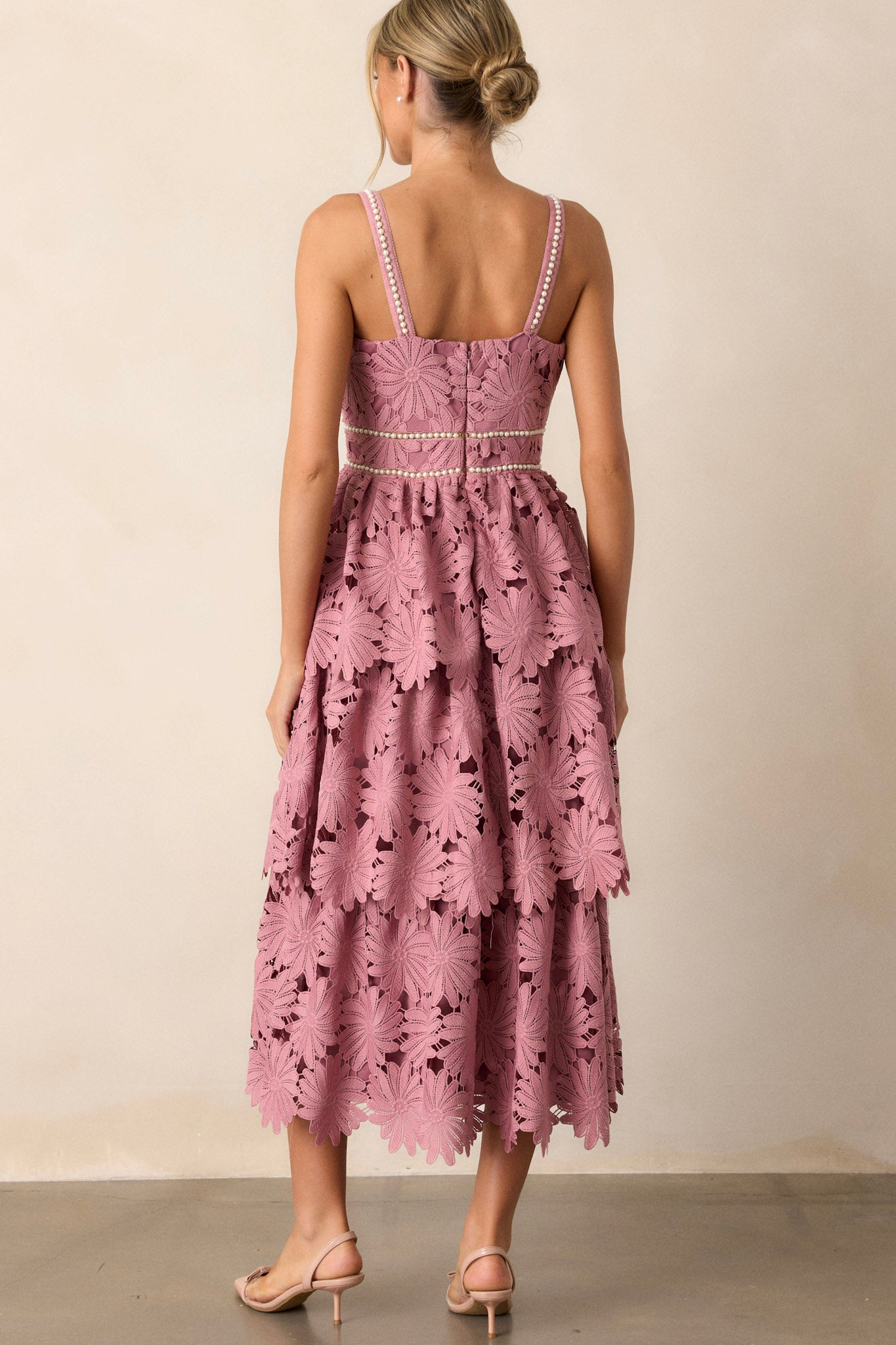 Back view of the dusty pink dress highlighting the discrete back zipper and the elegant flow of the lace tiered design.