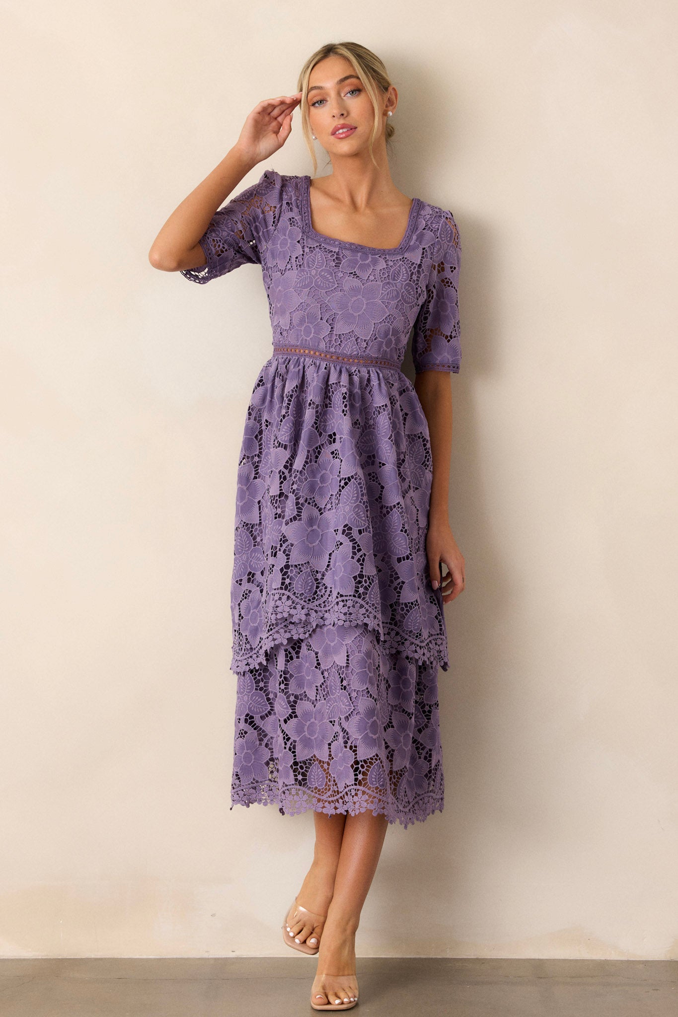 Action shot of the lilac dress capturing the movement of the tiered skirt, highlighting the square neckline, lace floral design, and the lace cutout waist detailing.