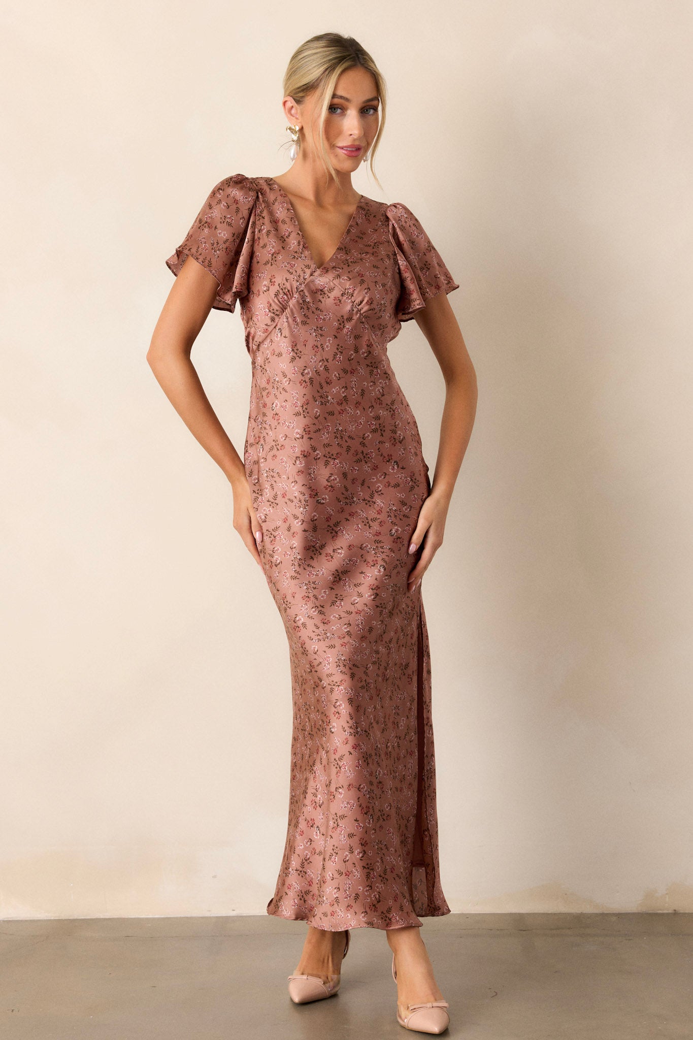 Front view of a dusty rose dress featuring a plunging v-neckline, flutter sleeves, a functional back zipper, and a high leg slit