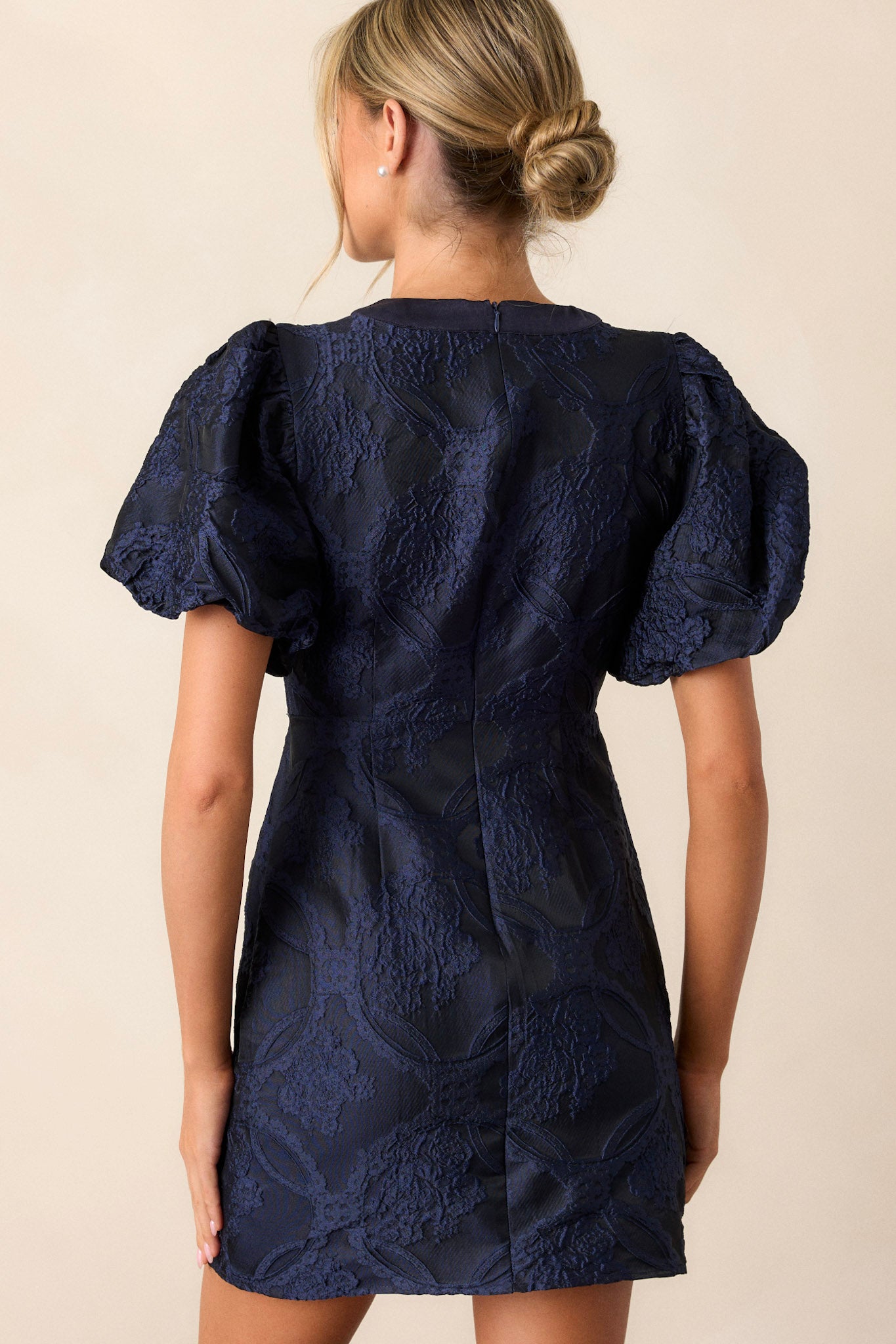 Back view of the navy dress highlighting the discrete back zipper and the continuation of the smooth silhouette.