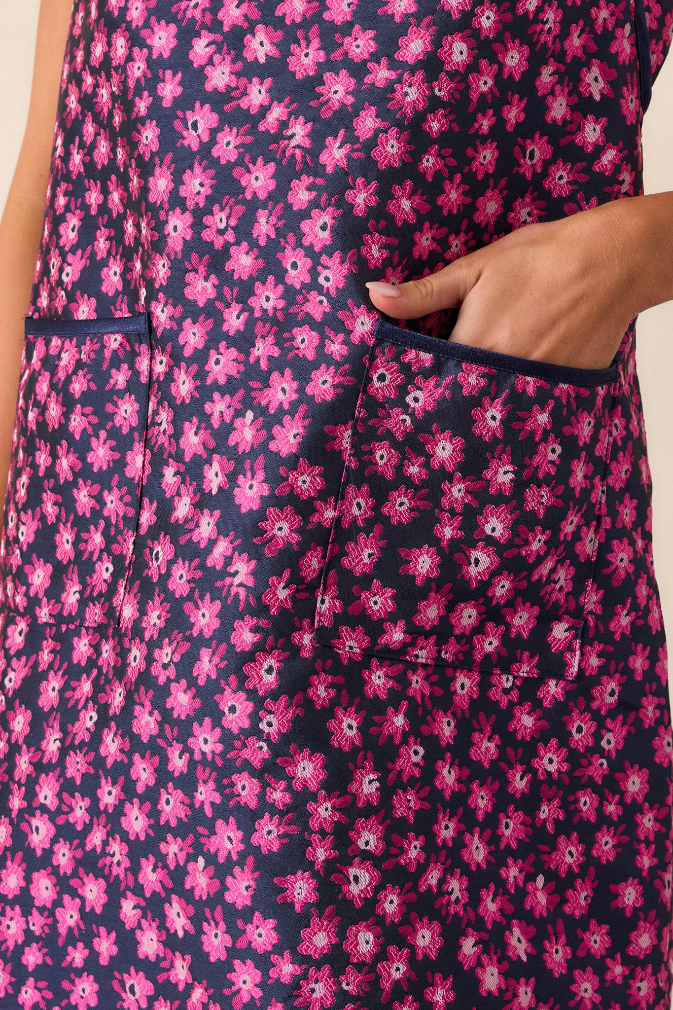 Close-up of the magenta mini dress focusing on the floral embroidery, rounded neckline, brown trim, and functional front pockets.