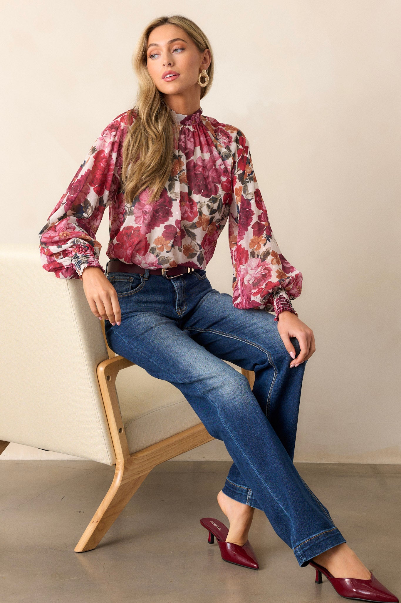 Seated full-length view of a model wearing dark wash jeans, emphasizing the high waisted design, faded thighs and knees, and the straight leg fit.