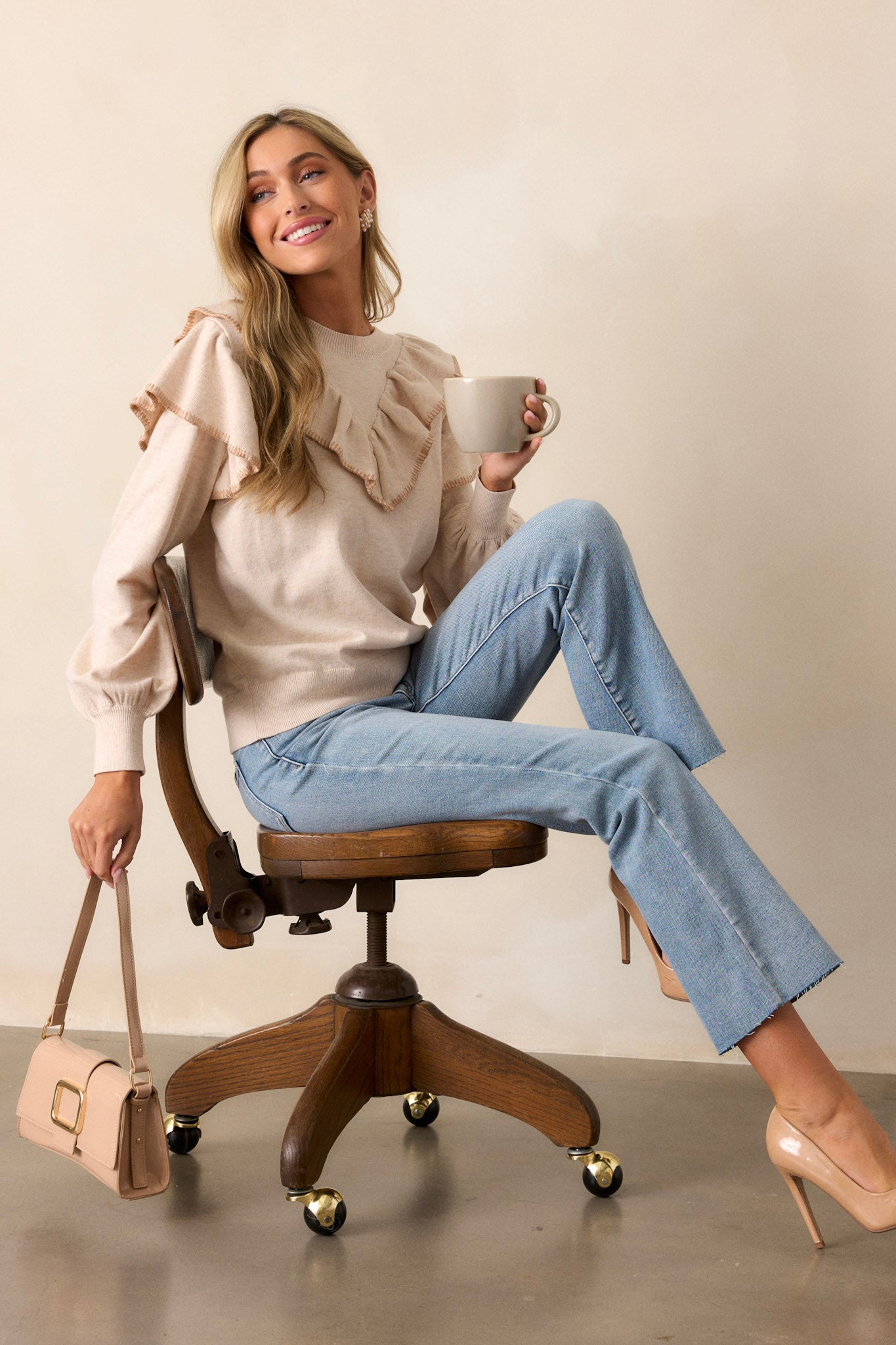 This beige top features a high neckline, a ruffle detail across the shoulders and chest, a ribbed hemline and cuffed long sleeves with a ruffle detailing on the top