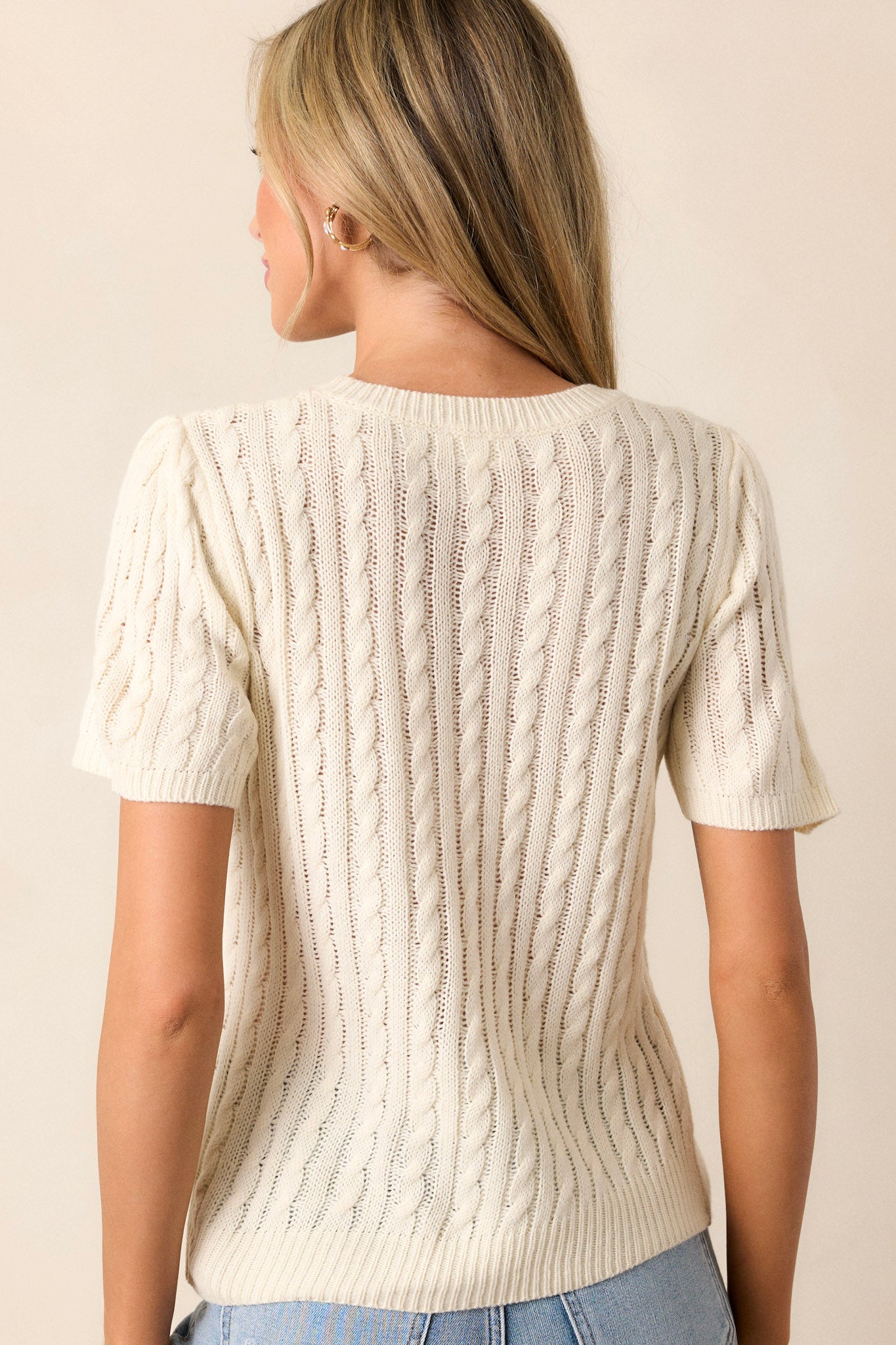 Back view of the top highlighting the cable knit design and the ribbed collar, wrists, and hips.