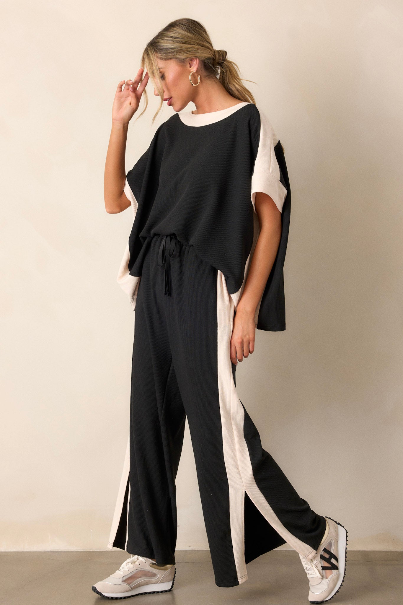 These black and ivory pants feature an elastic waist band, a high waisted design, a waist drawstring, a soft ribbed texture, functional hip pockets, a white trim down the side of the legs and high slits in the legs.