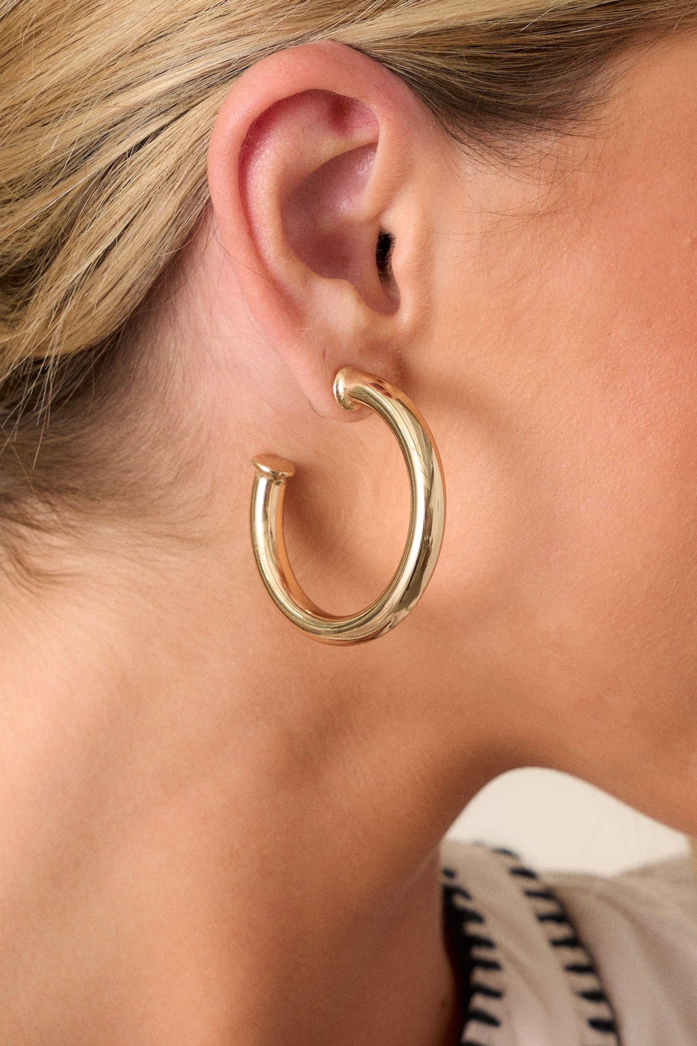 Close up view of these hoop earrings feature a gold finish and a secure post-back closure.