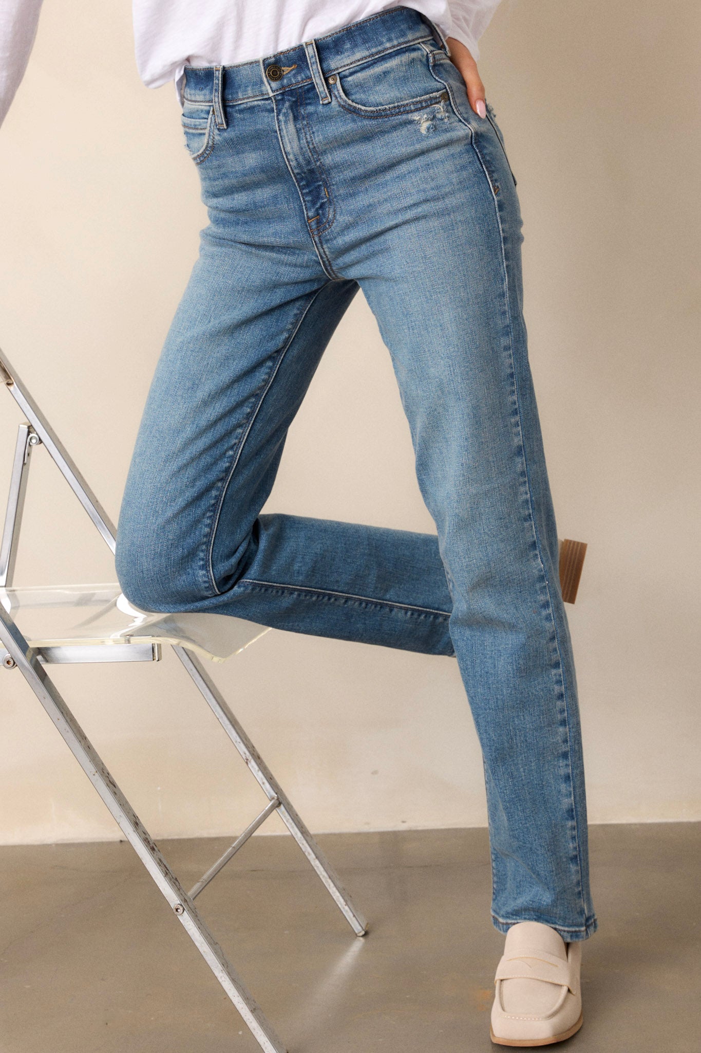 Front view of medium wash straight leg jeans featuring a high waist design, functional front & back pockets, distressed pocket detailing, a button & zipper closure, and a straight leg.