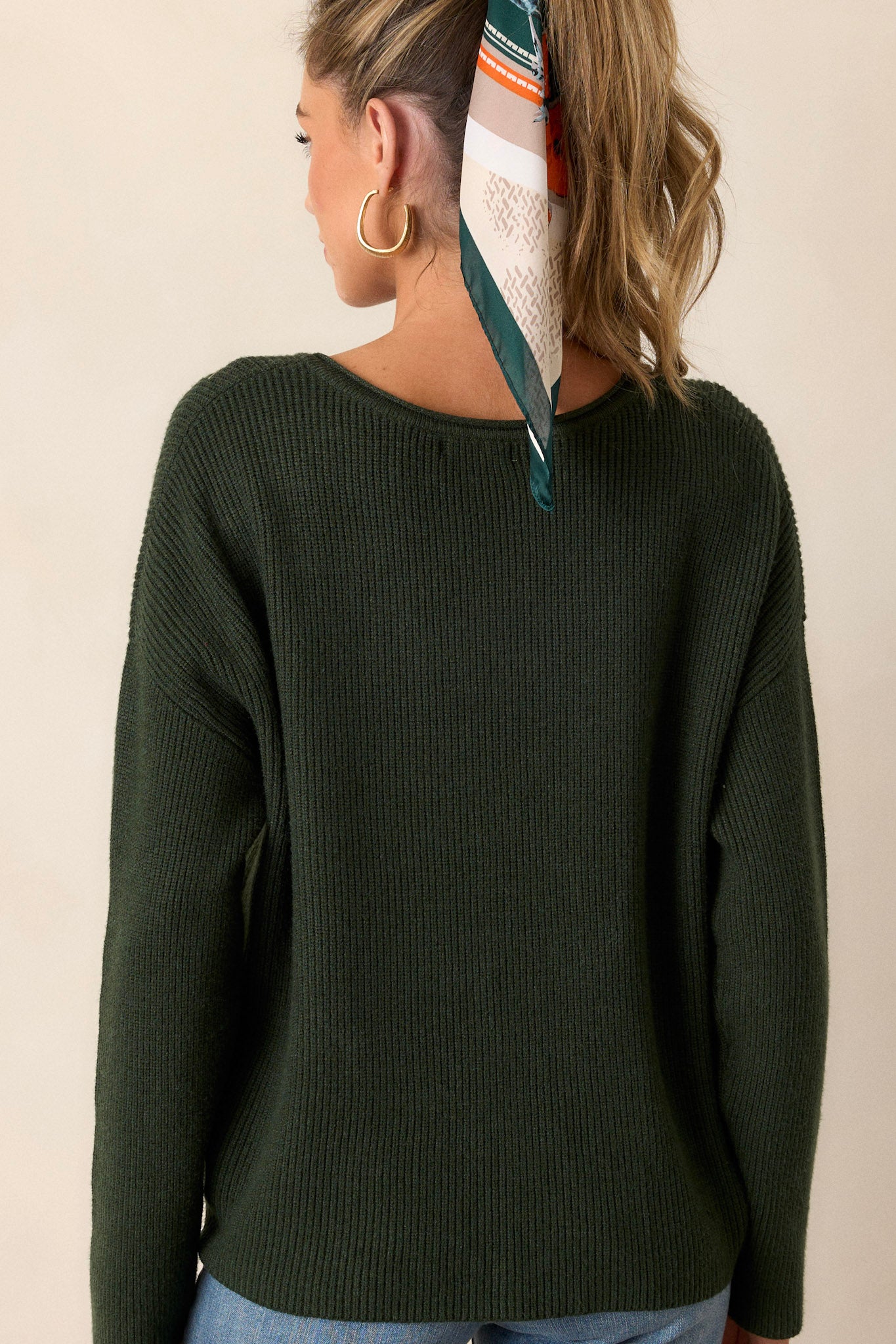 Back view of the green sweater highlighting the ribbed design and the back of the v-neckline, displaying the overall fit of the comfortable fabric