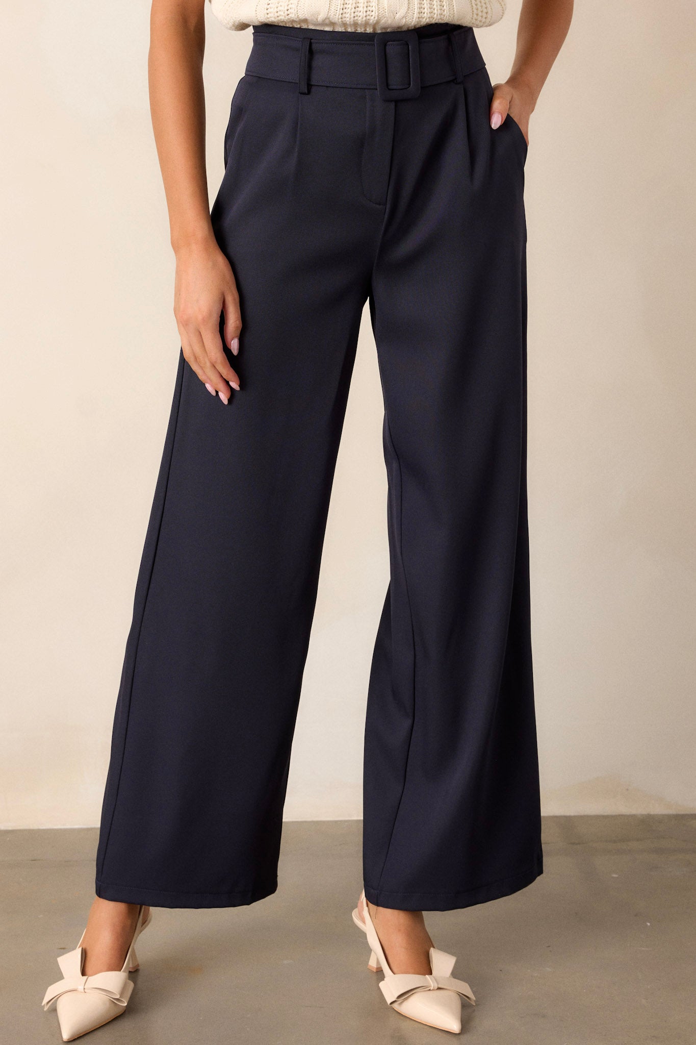 Front angled view of navy belted pants featuring a high waisted design, a hook and bar closure, a built-in adjustable cloth belt, functional pockets, and a wide leg