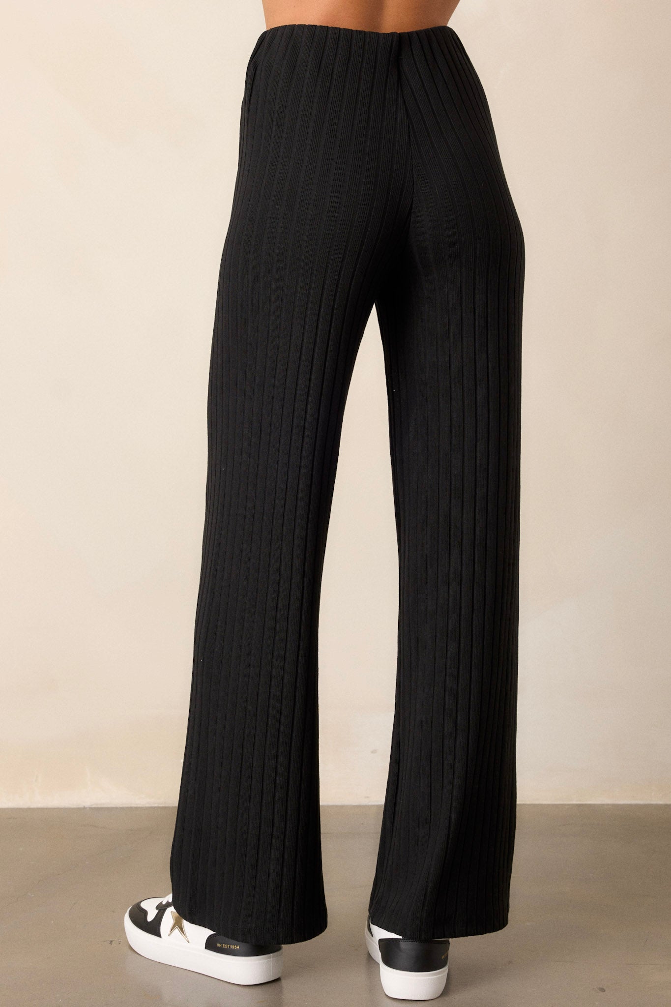 Back view of the black pants showcasing the straight leg cut and the sleek fit of the ribbed fabric with the high waisted design.