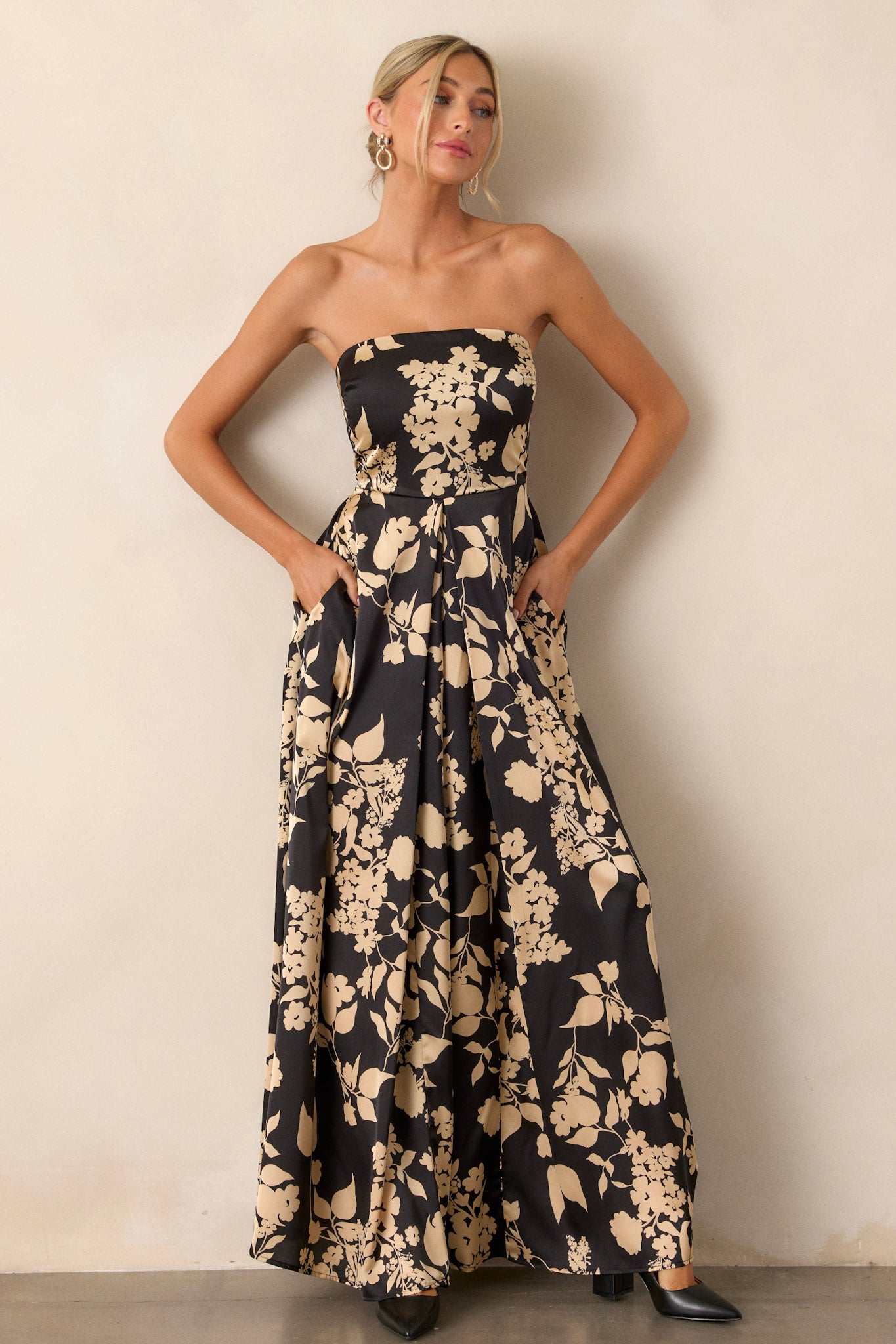 Angled view of the black jumpsuit displaying the floral pattern, sleeveless cut, and wide leg silhouette, capturing the playful and stylish essence of the garment