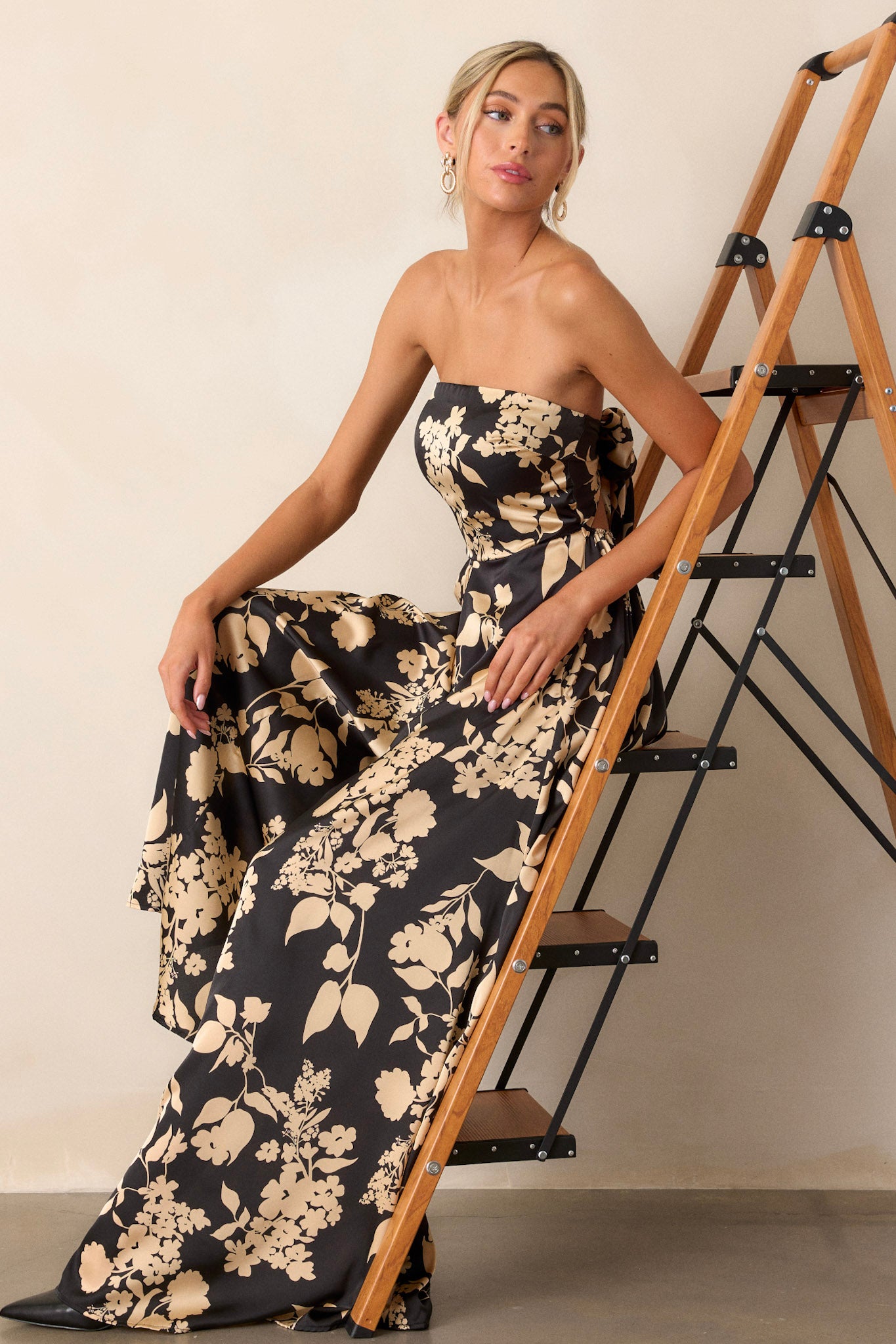 Side view of the black jumpsuit highlighting the bold floral design, the sleeveless cut, and the flowy wide leg silhouette