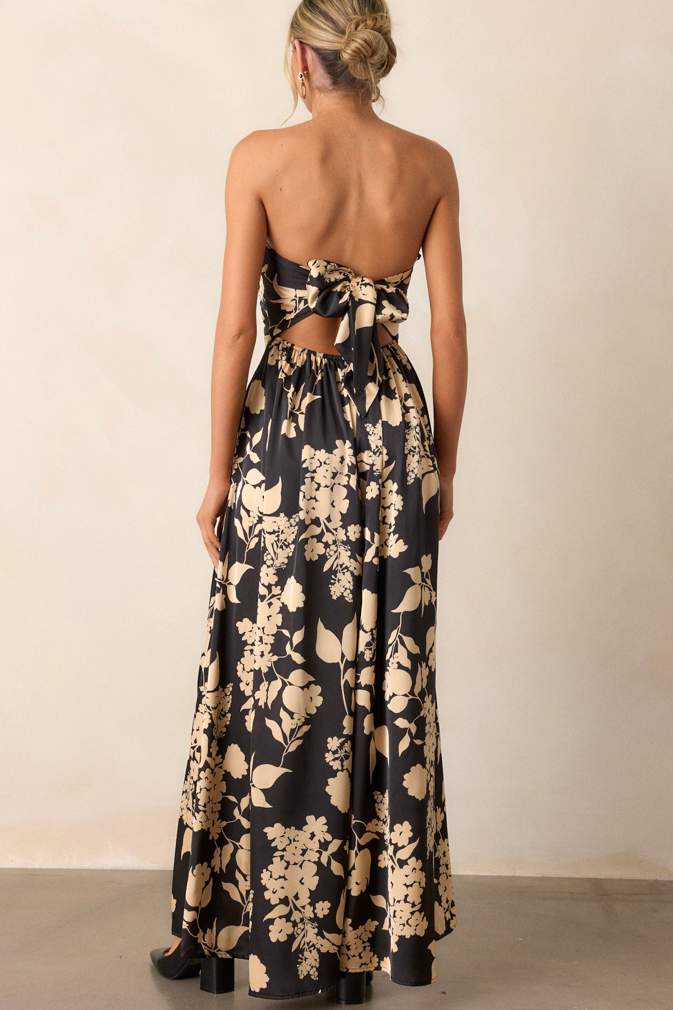 Back view of the black jumpsuit showcasing the continuous floral pattern, the sleeveless design, and the wide leg silhouette