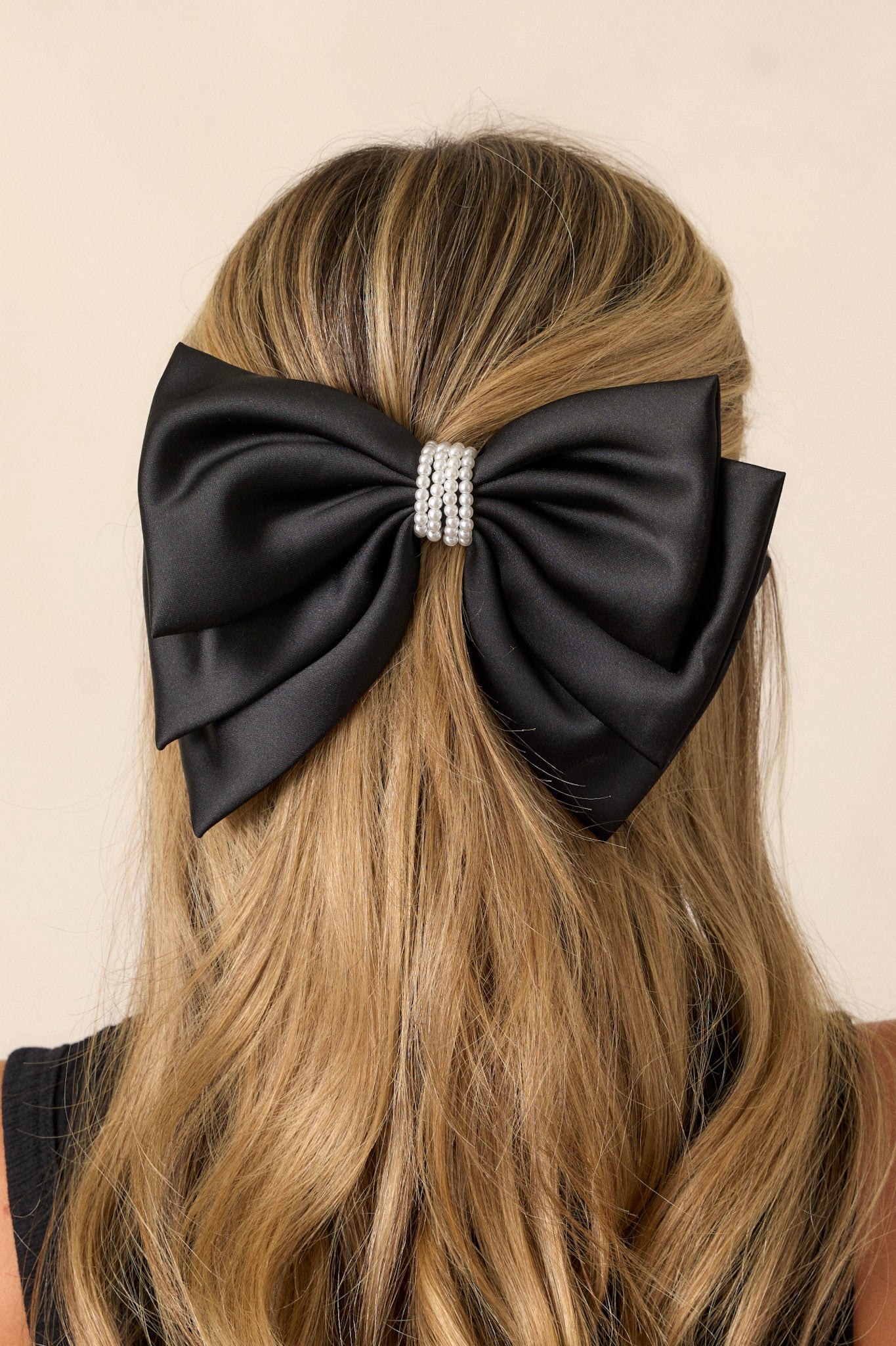 This black bow features a multi layer design, a pearl center, and a barrette clip.