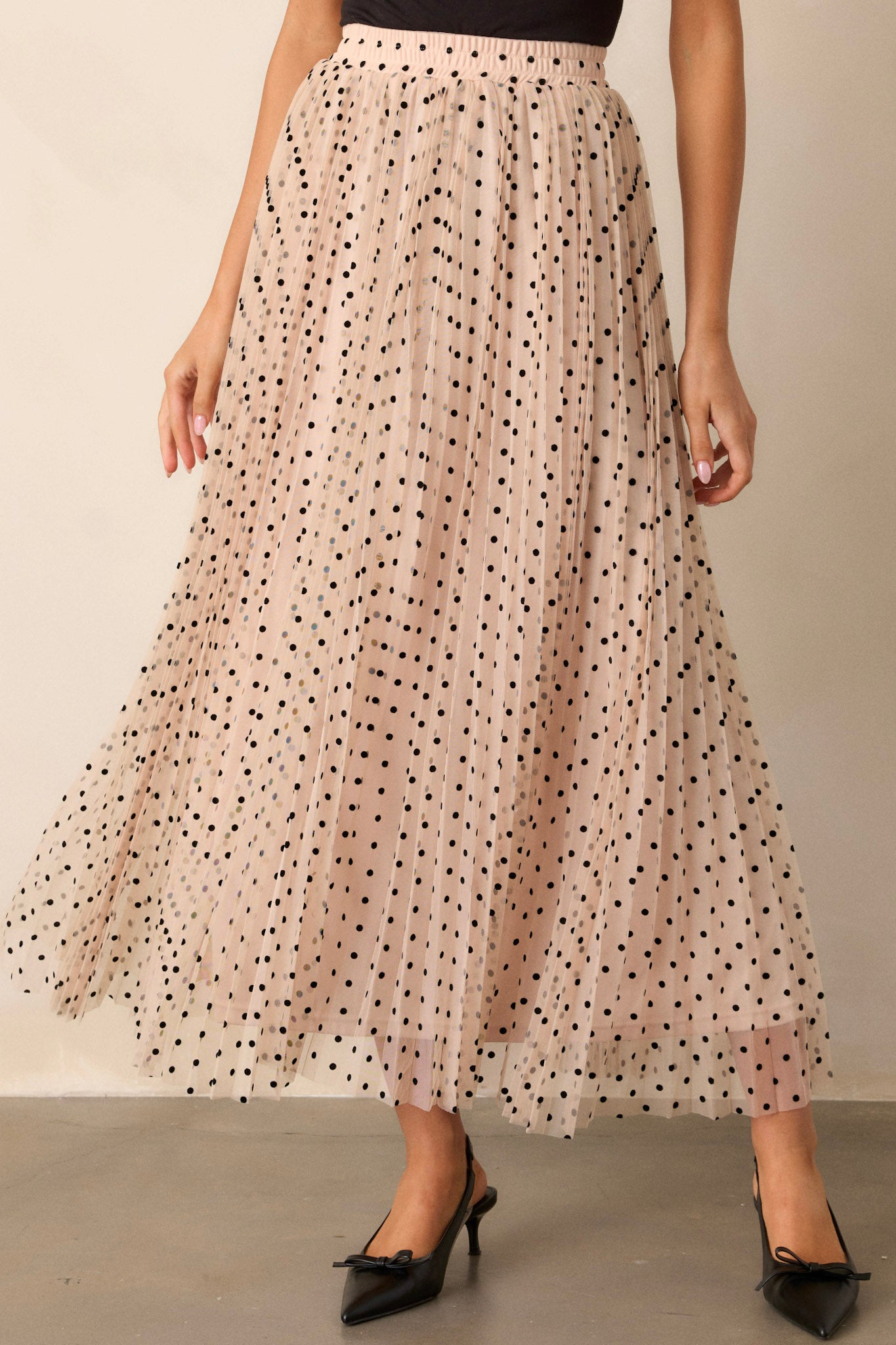 Front view of this polka dot beige skirt featuring a high waisted design, an elastic waist band, a pleated design, and a flowing silhouette.