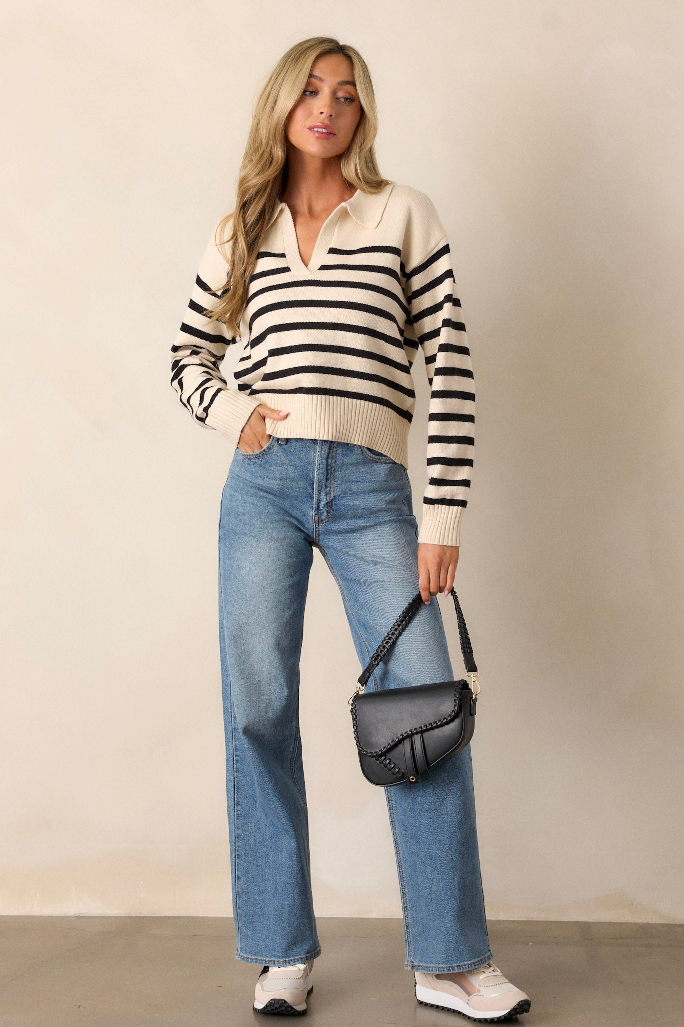 Full body view of a beige sweater featuring a v-neckline with a collar, classic black horizontal stripes, long sleeves, and a ribbed hem and cuffs.