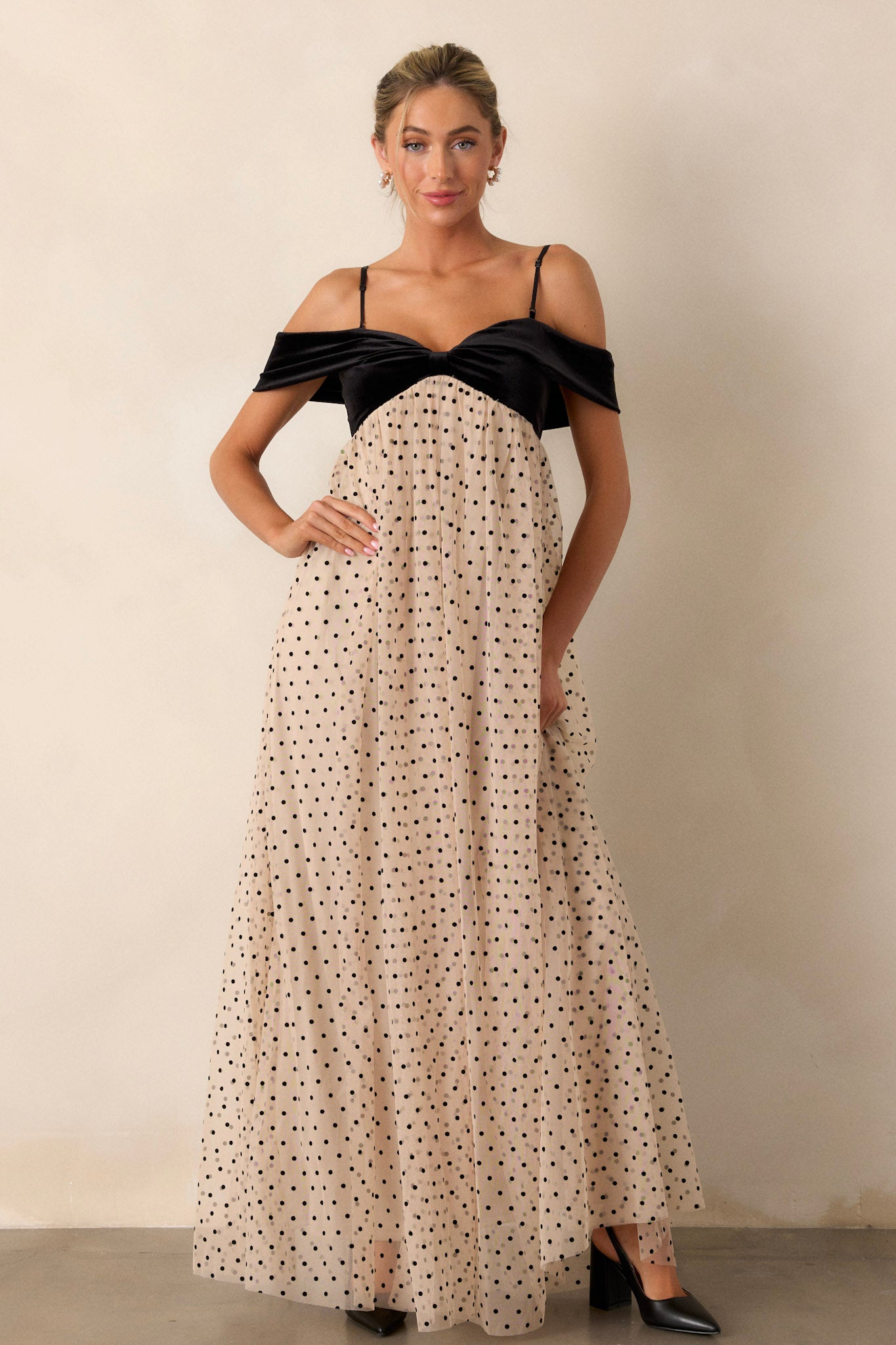 Full-length view of a model wearing the dress, emphasizing the velvet bust, the bow-shaped off-the-shoulder design, the flowy polka dot skirt, and the overall silhouette.