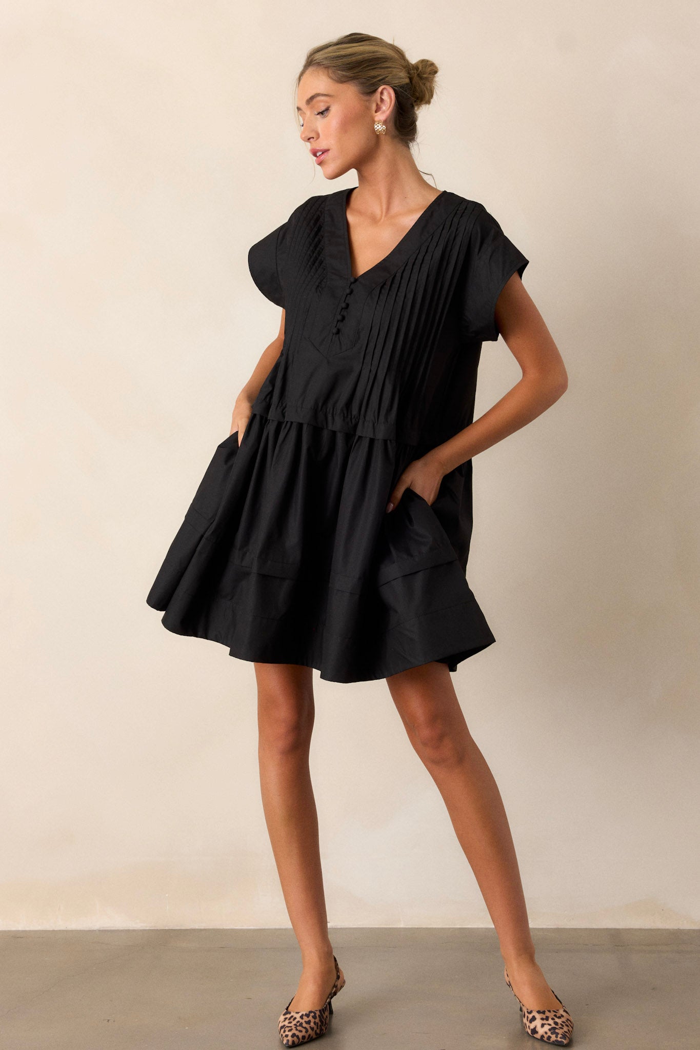 This black dress features a deep v-neck, a functional button-front and two functional side pockets