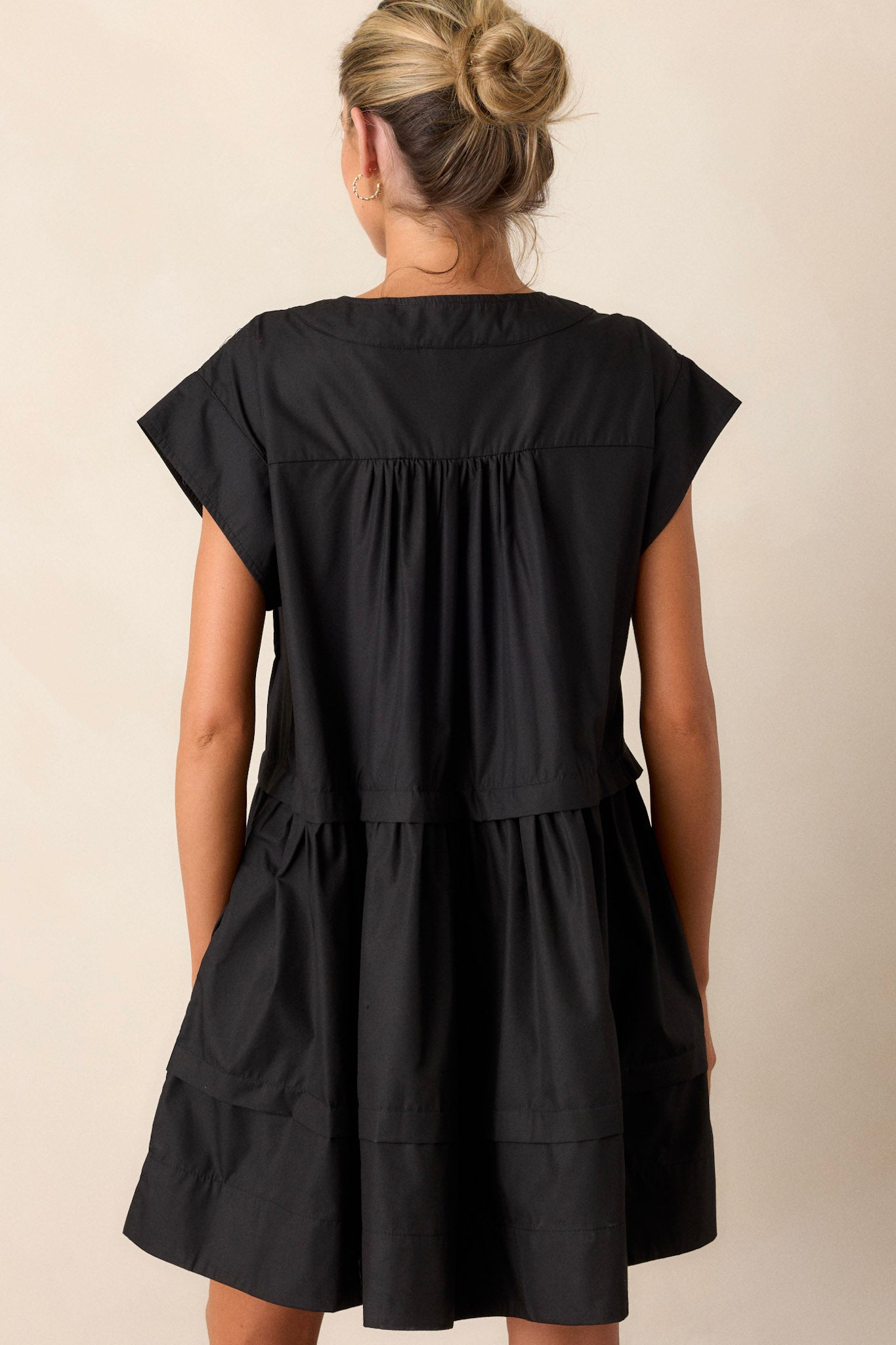 Back view of the black dress highlighting the simple, elegant design with a focus on the overall silhouette.