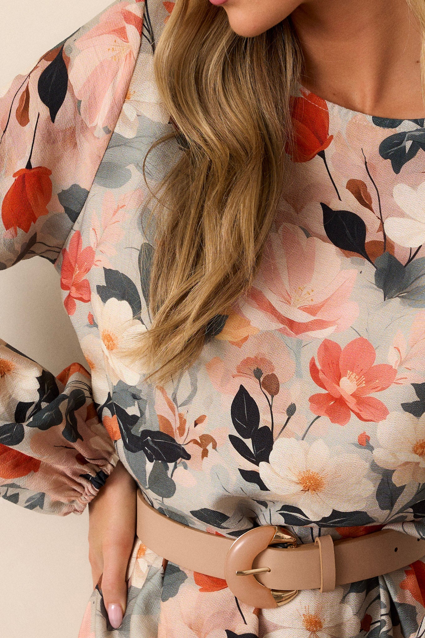 Close-up of the green floral dress focusing on the high neckline, the orange and white floral print, the ruffled hem, and the elastic cuffed long sleeves.