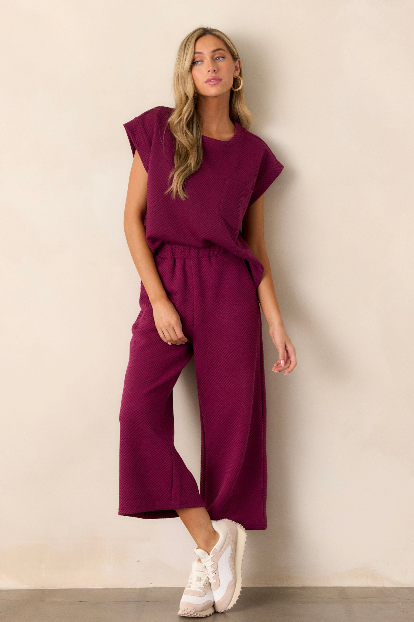 Full-length view of a model wearing the sangria purple top, emphasizing the crew neckline, the functional breast pocket, the subtle crisscross texturing, and the wide cuffed short sleeves.