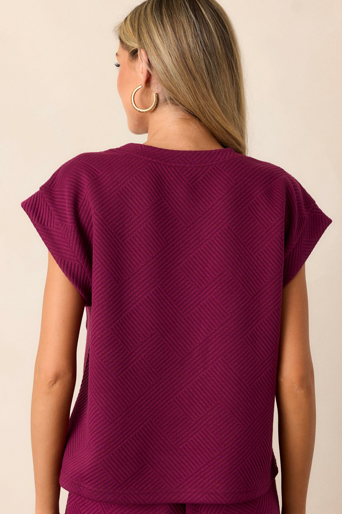 Back view of the sangria purple top highlighting the crew neckline, the subtle crisscross texturing, and the fit of the wide cuffed short sleeves