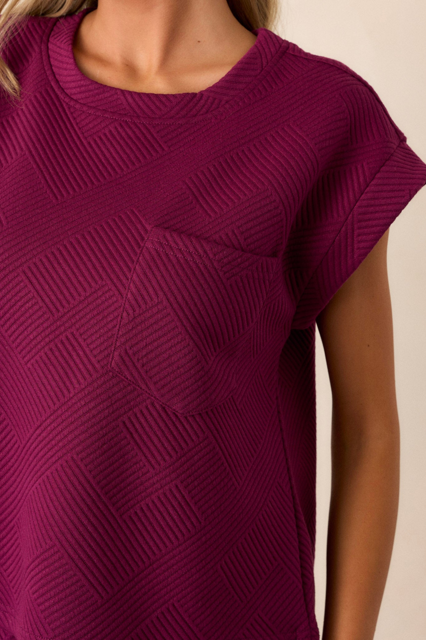 Close-up of the sangria purple top focusing on the crew neckline, the functional breast pocket, the subtle crisscross texturing, and the wide cuffed short sleeves.