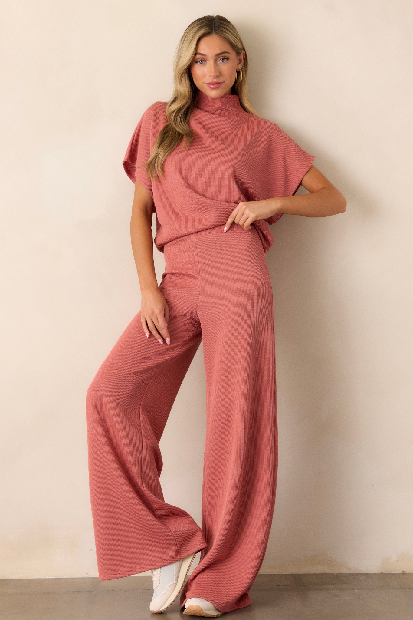 Full body view of these coral knitted pants that feature an elastic waist band, a high waisted design, a knit towel like texture on the outside, a soft inside and a wide leg.