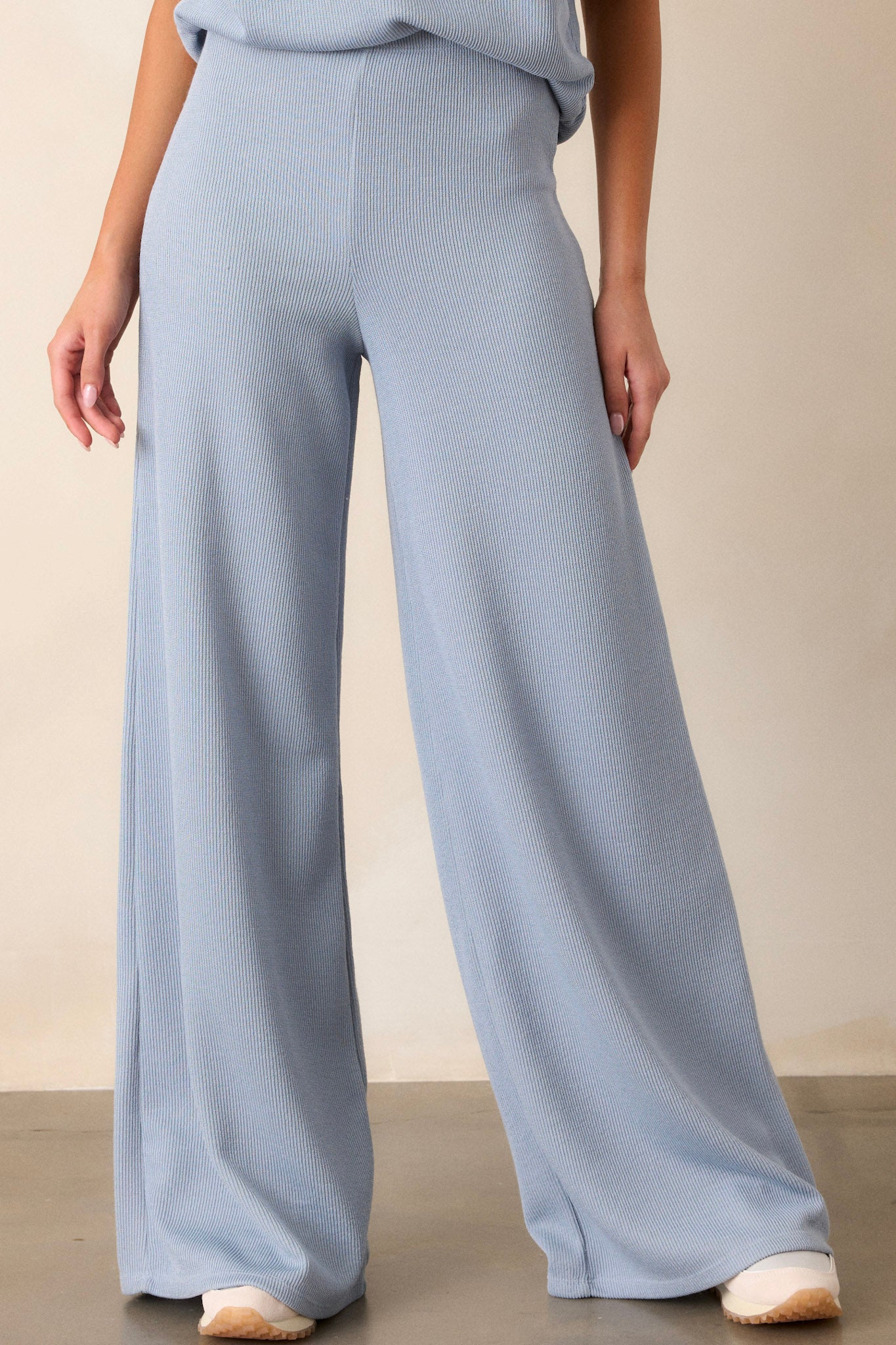 Angled front view of these blue knitted pants that feature an elastic waist band, a high waisted design, a knit towel like texture on the outside, a soft inside and a wide leg.