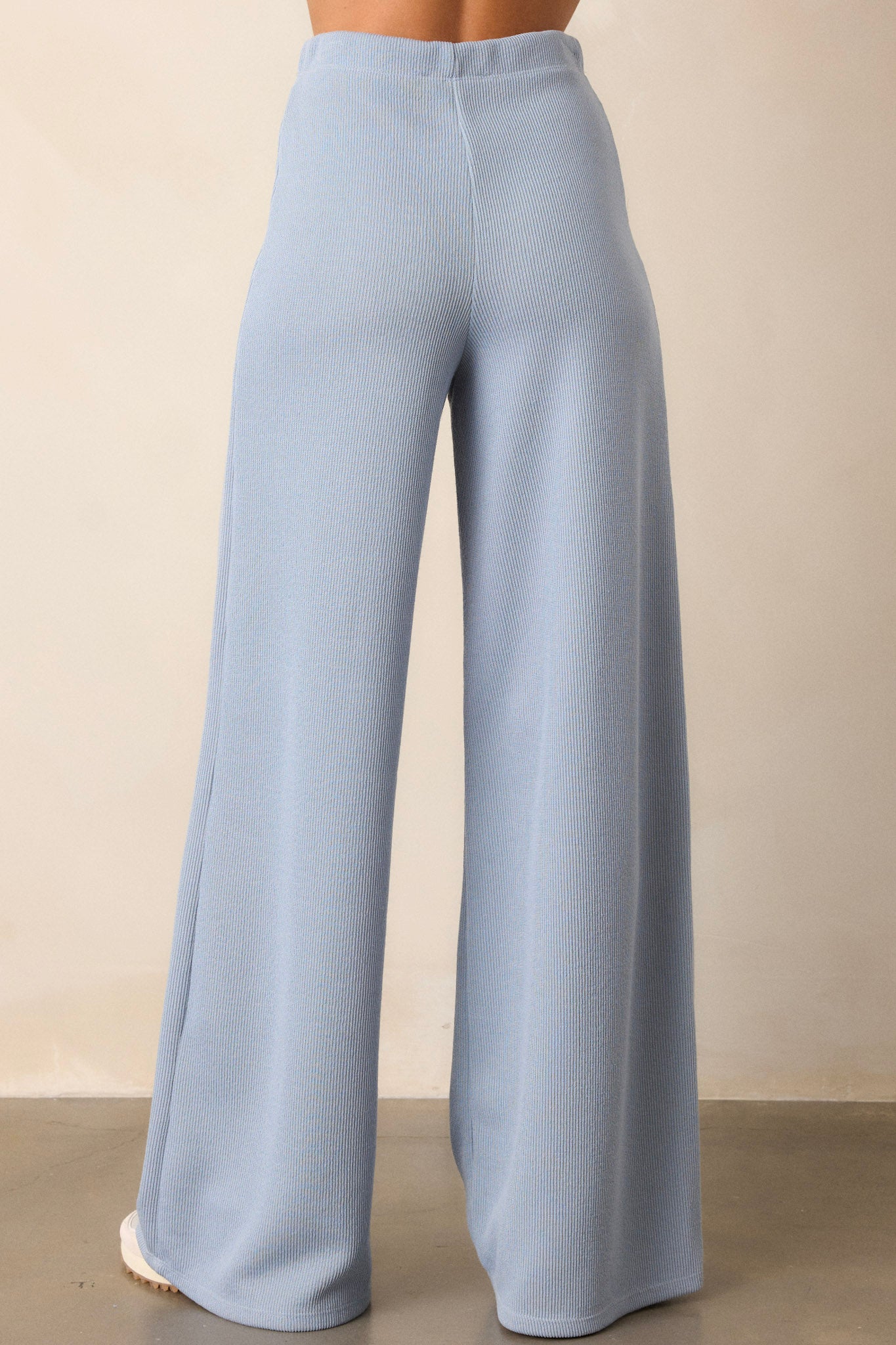 Back view of these blue knitted pants that feature an elastic waist band, a high waisted design, a knit towel like texture on the outside, a soft inside and a wide leg.