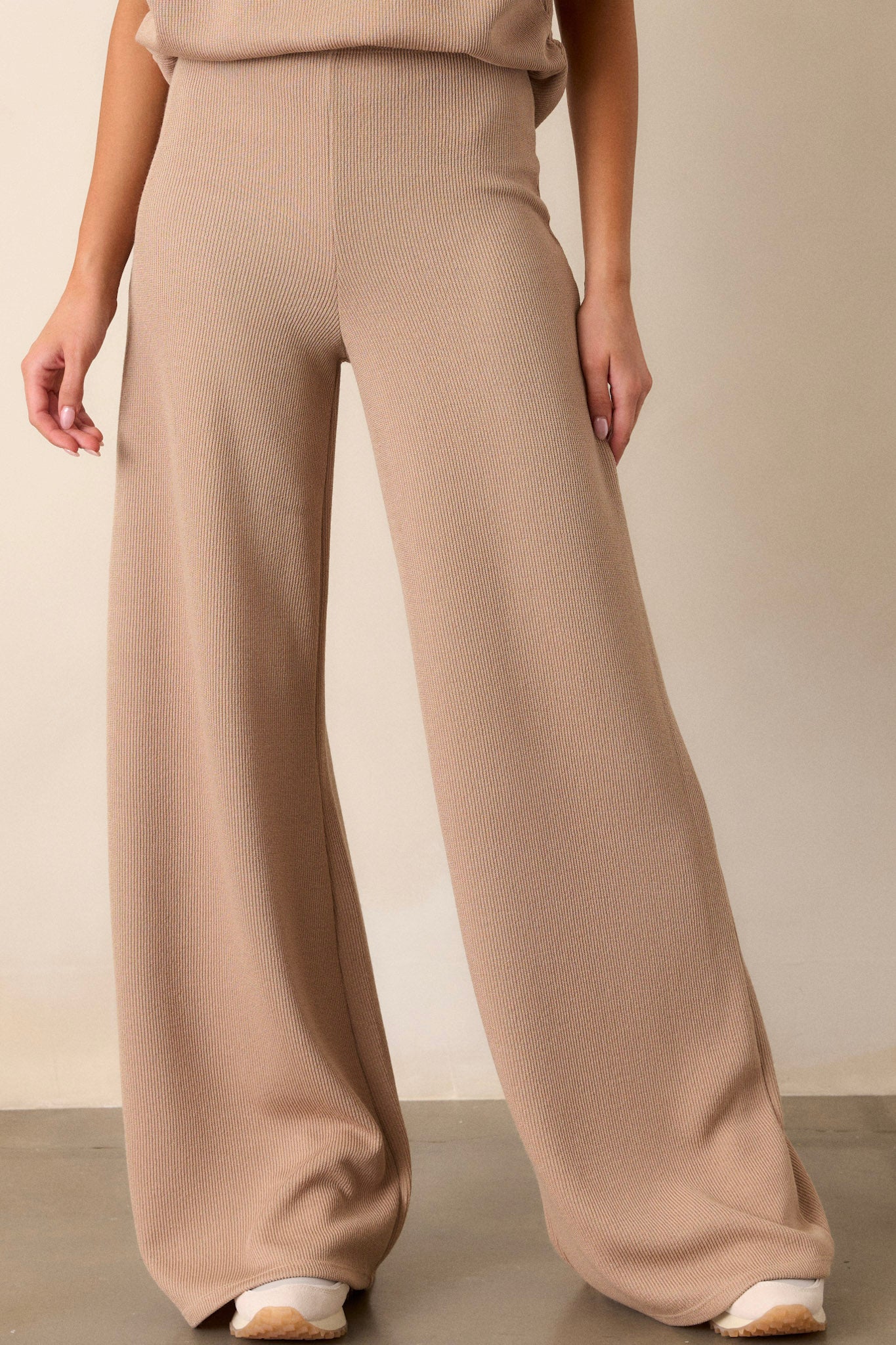 Front view of beige knitted pants featuring an elastic waistband, a high-waisted design, a knit towel-like texture on the outside, a soft inside, and a wide leg