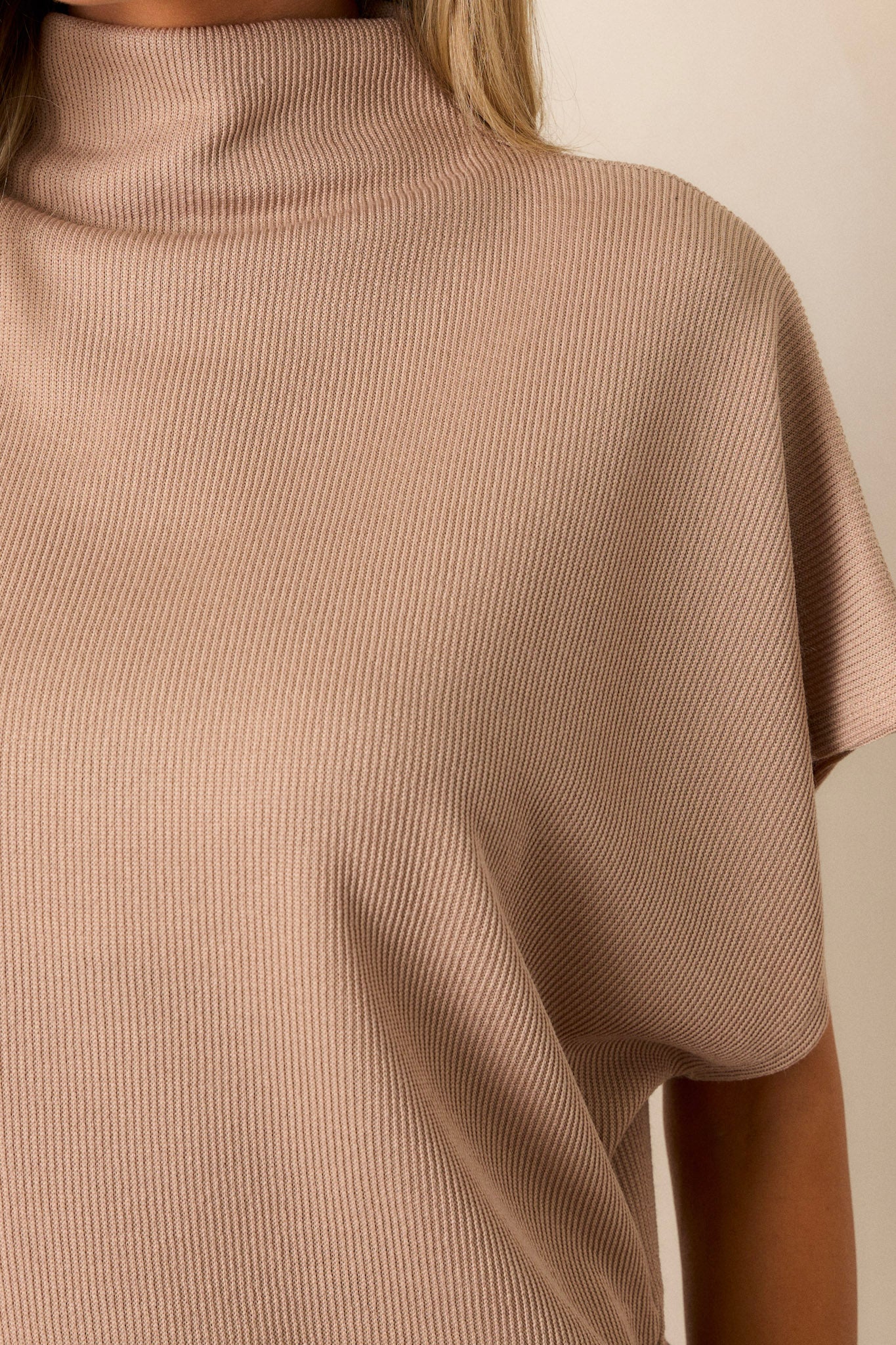 Close-up of the beige top focusing on the knit towel-like texture, turtleneck, and the soft smooth inside fabric.