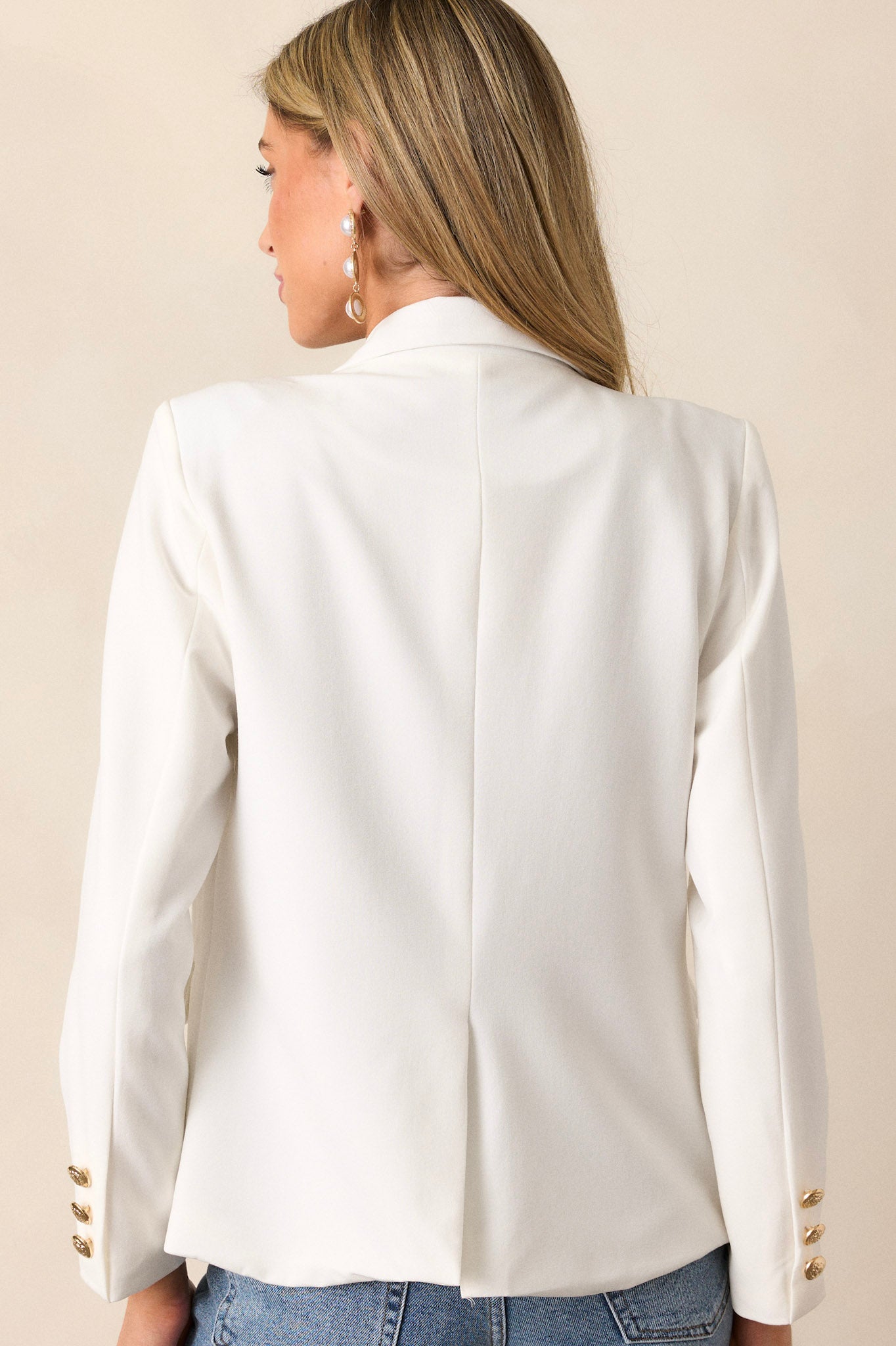 Back view of the white blazer highlighting the clean design of the back, with the v-neck collar subtly visible