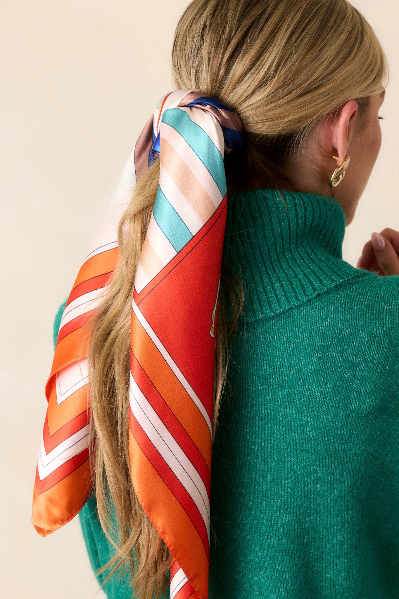 Front view of this orange scarf that features an orange trim, with accent colors of ivory, teal, orange and yellow, and a design with horses on it.