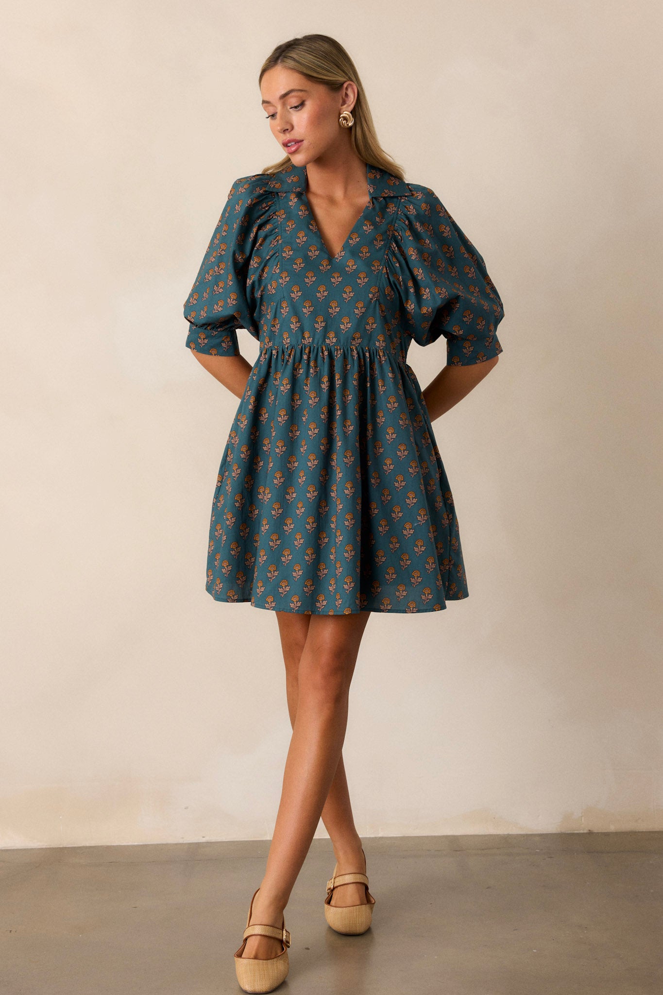 Full length view of a teal dress featuring a small v-neckline, puff sleeves, and side pockets