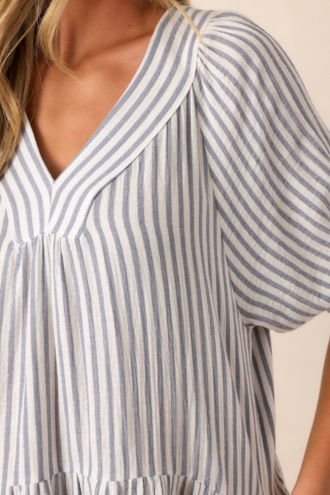 A close-up detail of the blue and ivory striped mini dress, highlighting the textured fabric and elastic cuffed short sleeves.