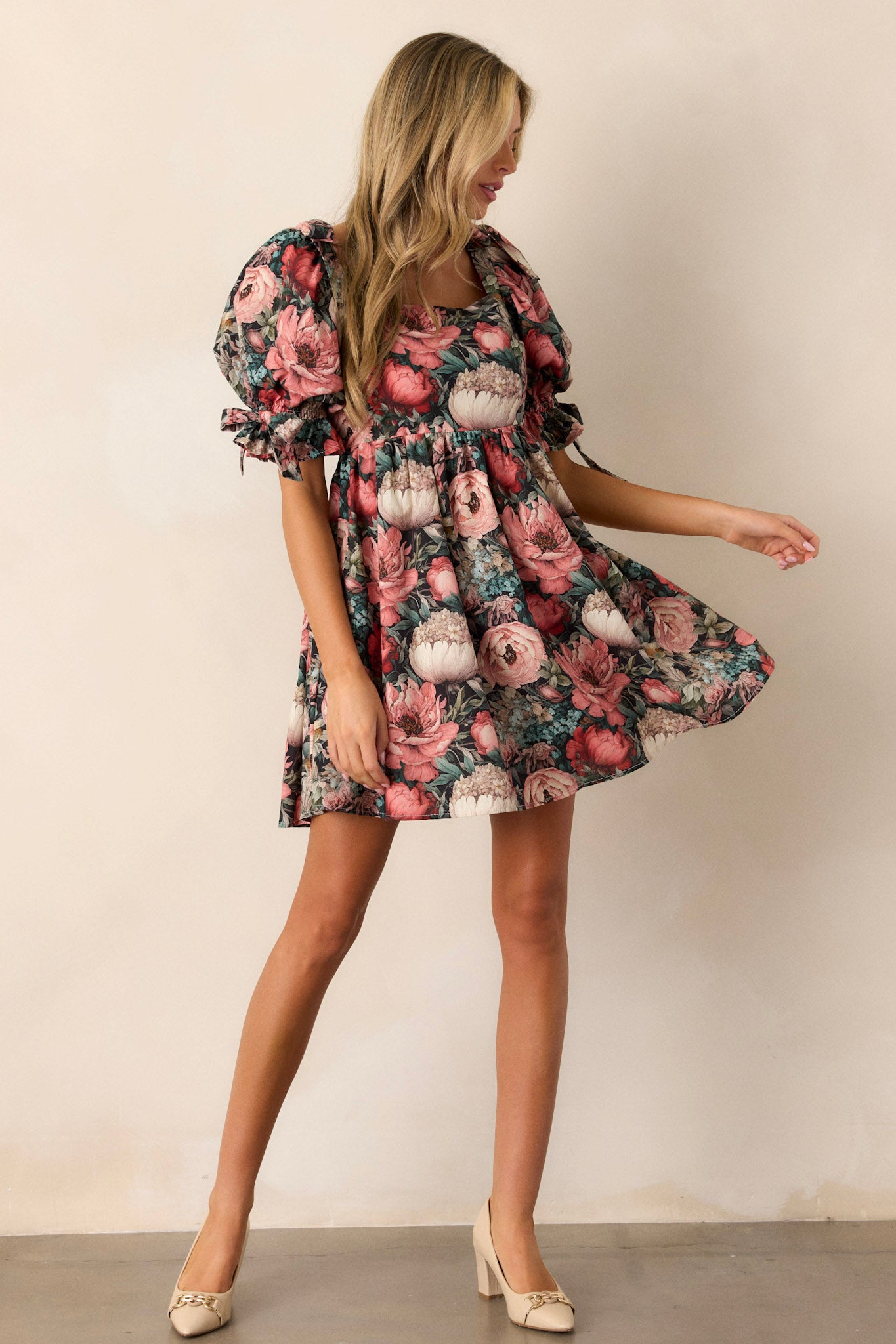 Front view of a dress featuring puff sleeves with ties, two functional side pockets, and a flowy floral tier.