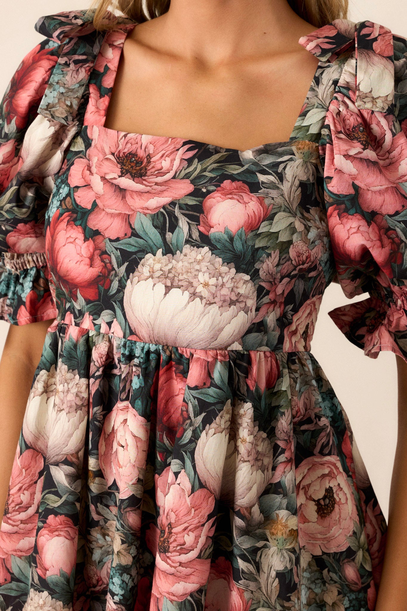 Close-up of the dress focusing on the puff sleeves with ties, the floral pattern, and the detailing of the functional side pockets.