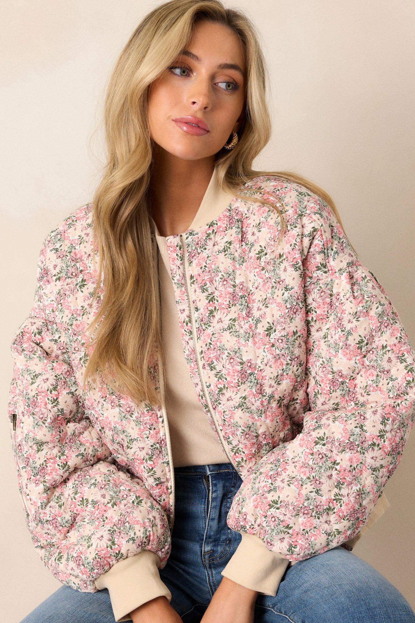 Angled front view of this pink floral jacket that features a full zip front, functional waist pockets, a functional zipper pocket on the right sleeve.