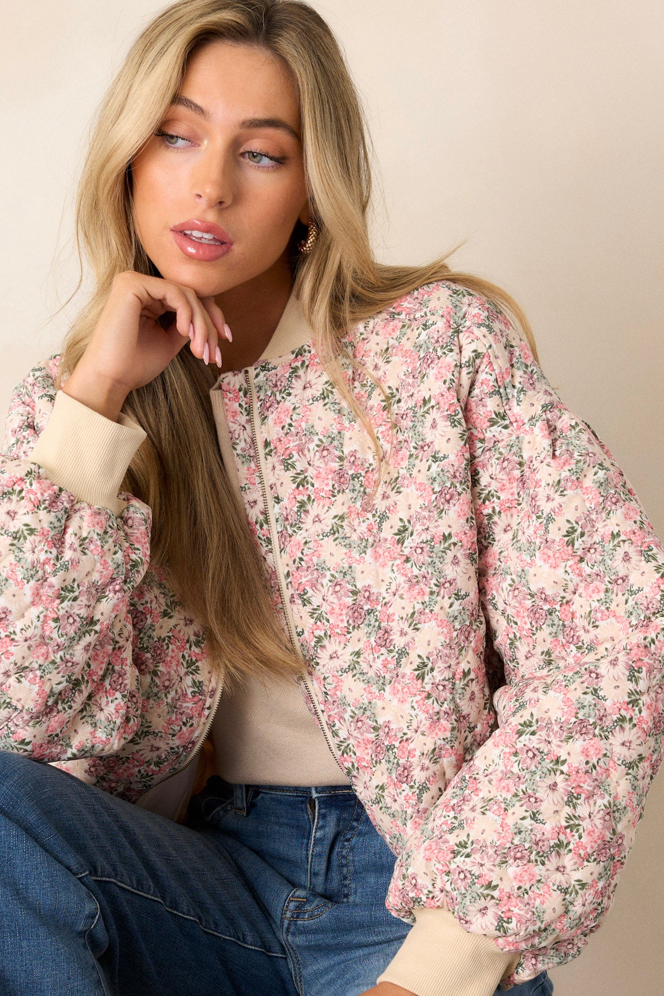 Front angled view of this pink floral jacket that features a full zip front, functional waist pockets, a functional zipper pocket on the right sleeve.