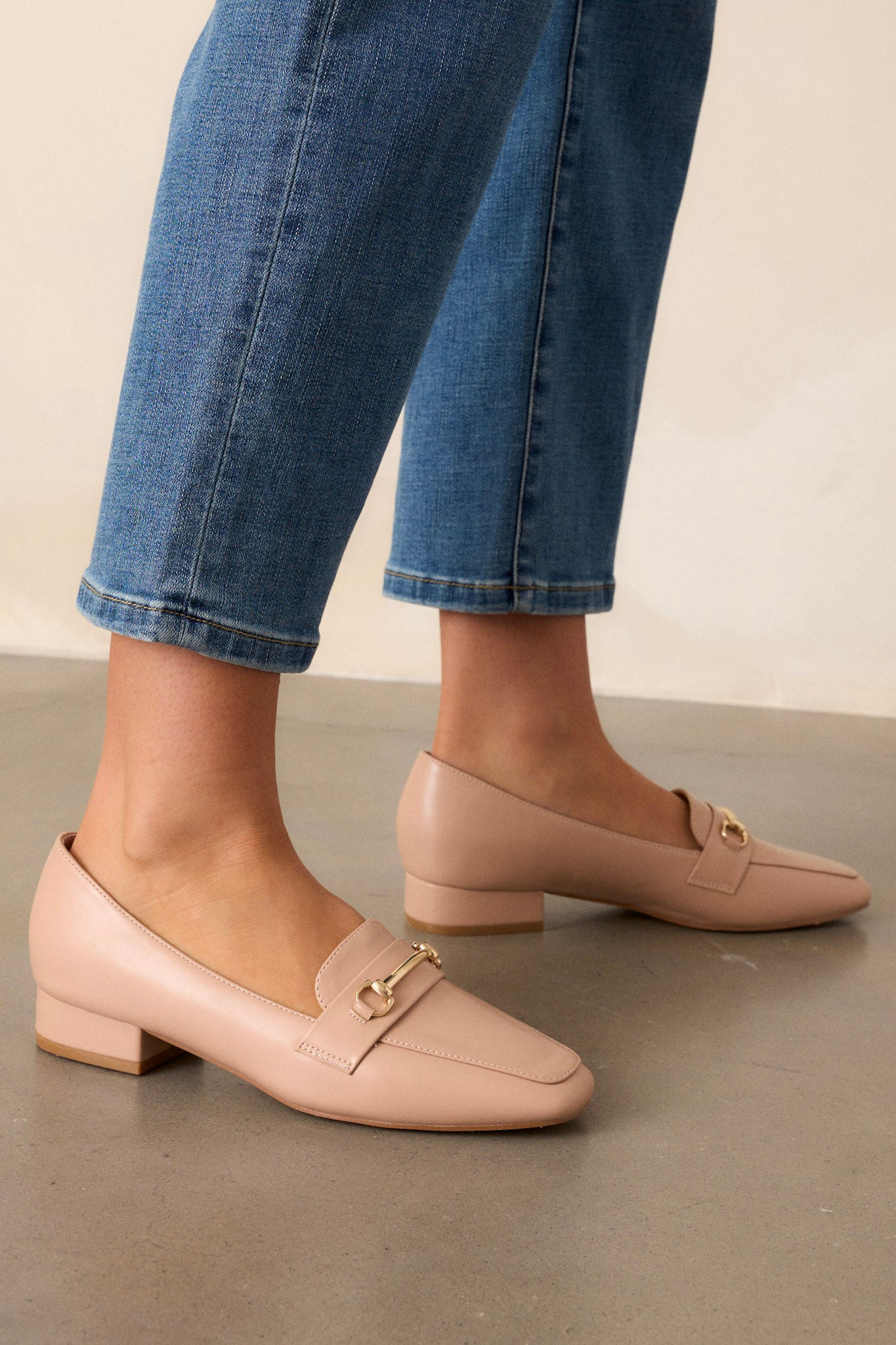 These beige loafers feature a slip on design, a small heel, a square toe, and gold hardware.