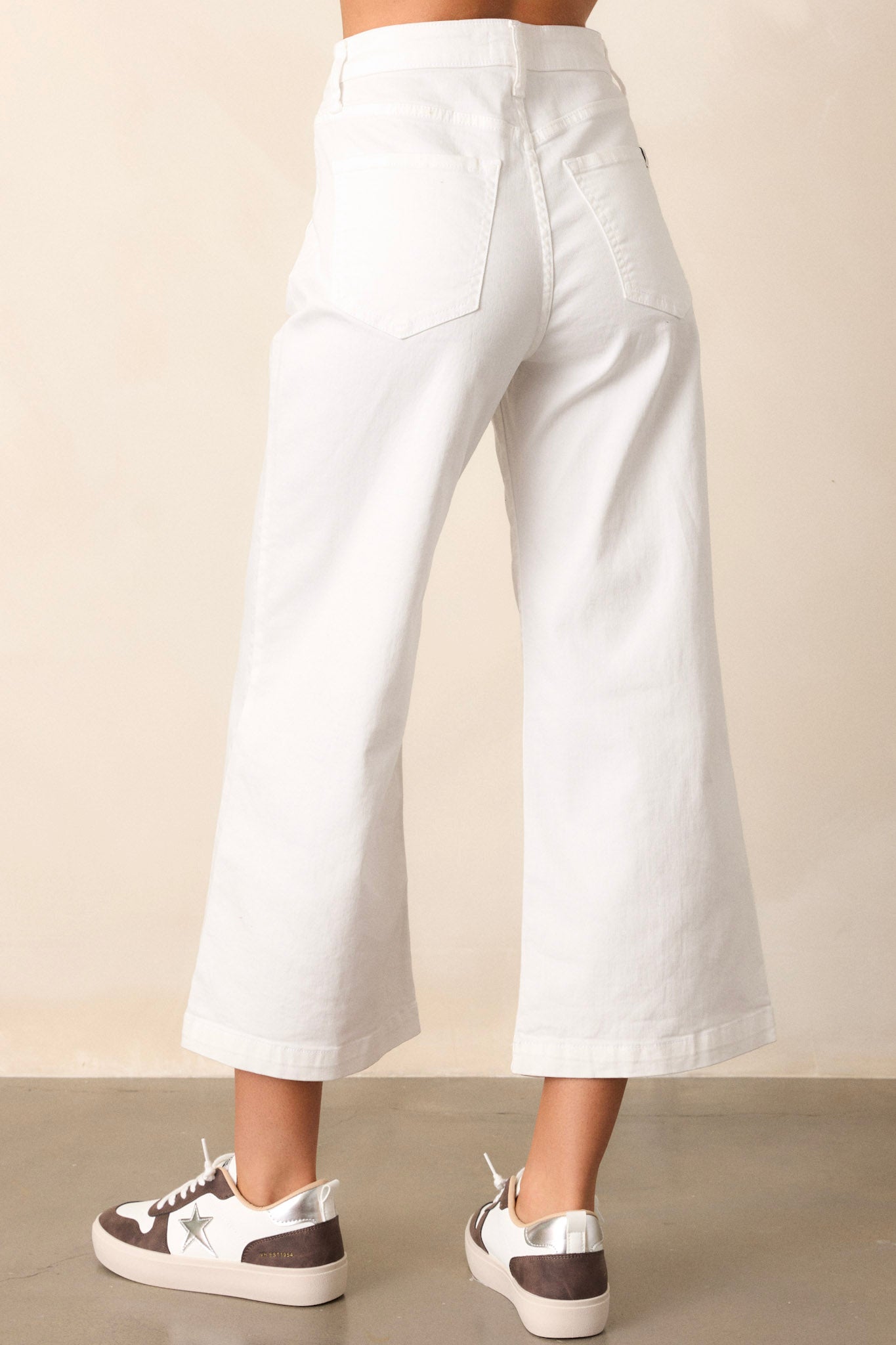 Back view of the white jeans showing the button & zipper closure, belt loops, and functional front pockets.